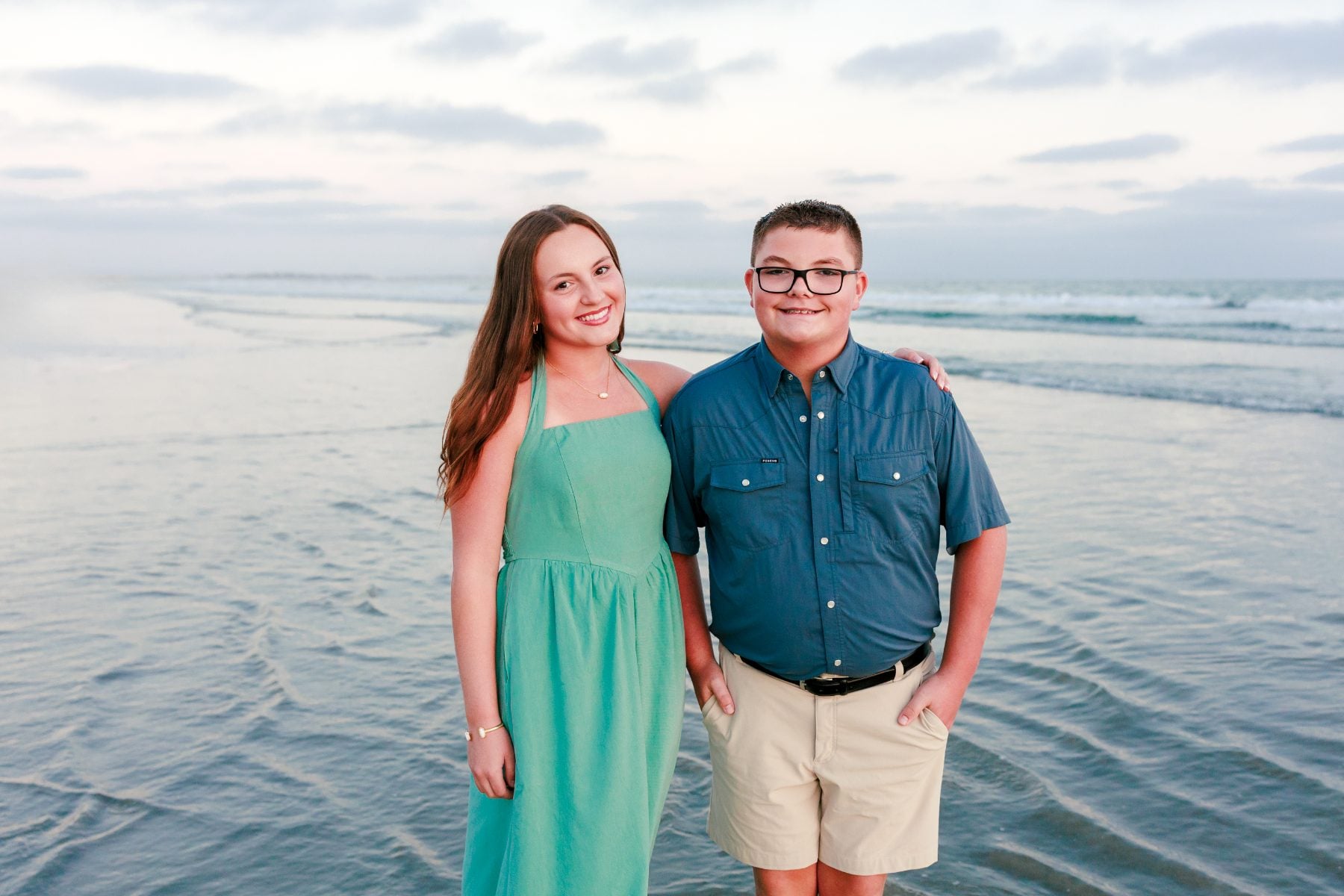 Sister and brother stand together on Coronado Beach at dusk