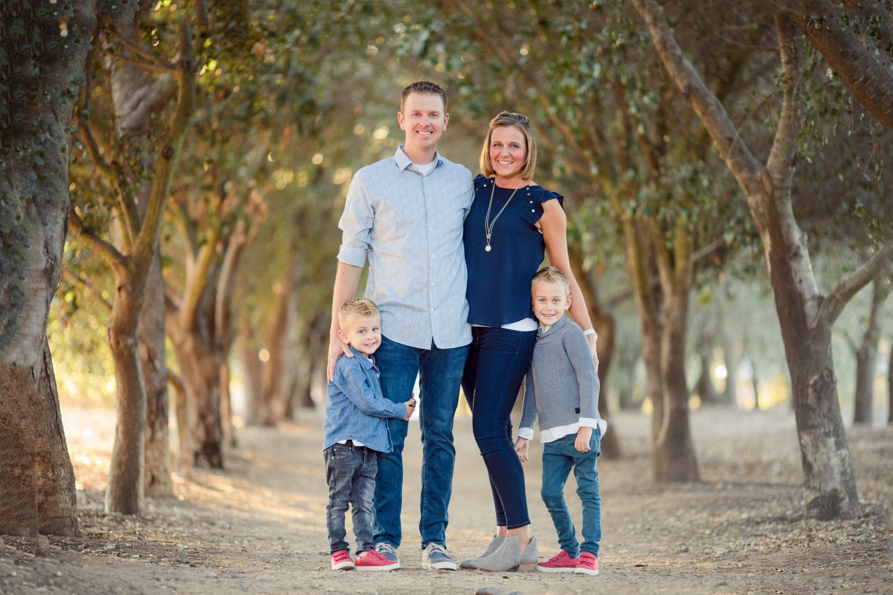 Butler family of five stands together on a shaded tree-lined path