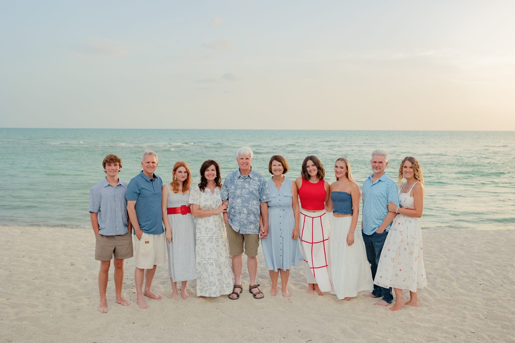 Ten-person extended family gathers on the beach at dusk