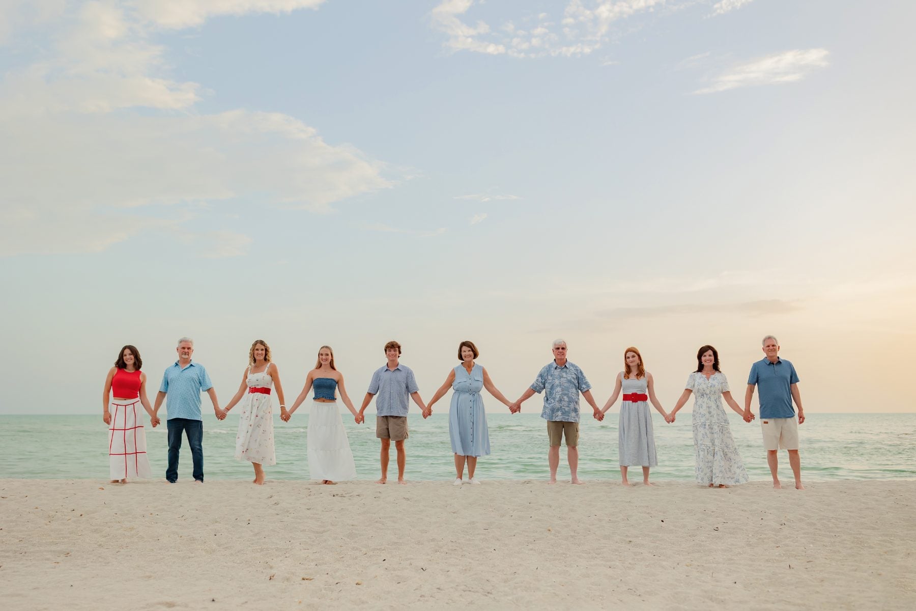 Extended family holds hands in a line on the beach