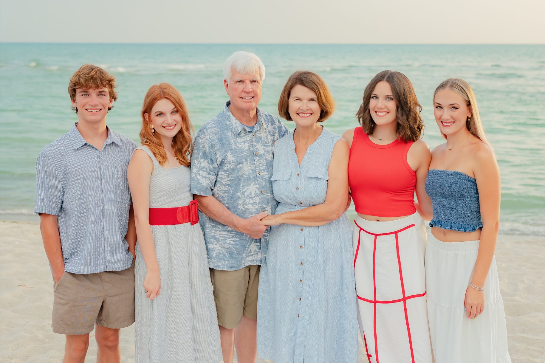 Extended family group of six stands on Captiva Island shore