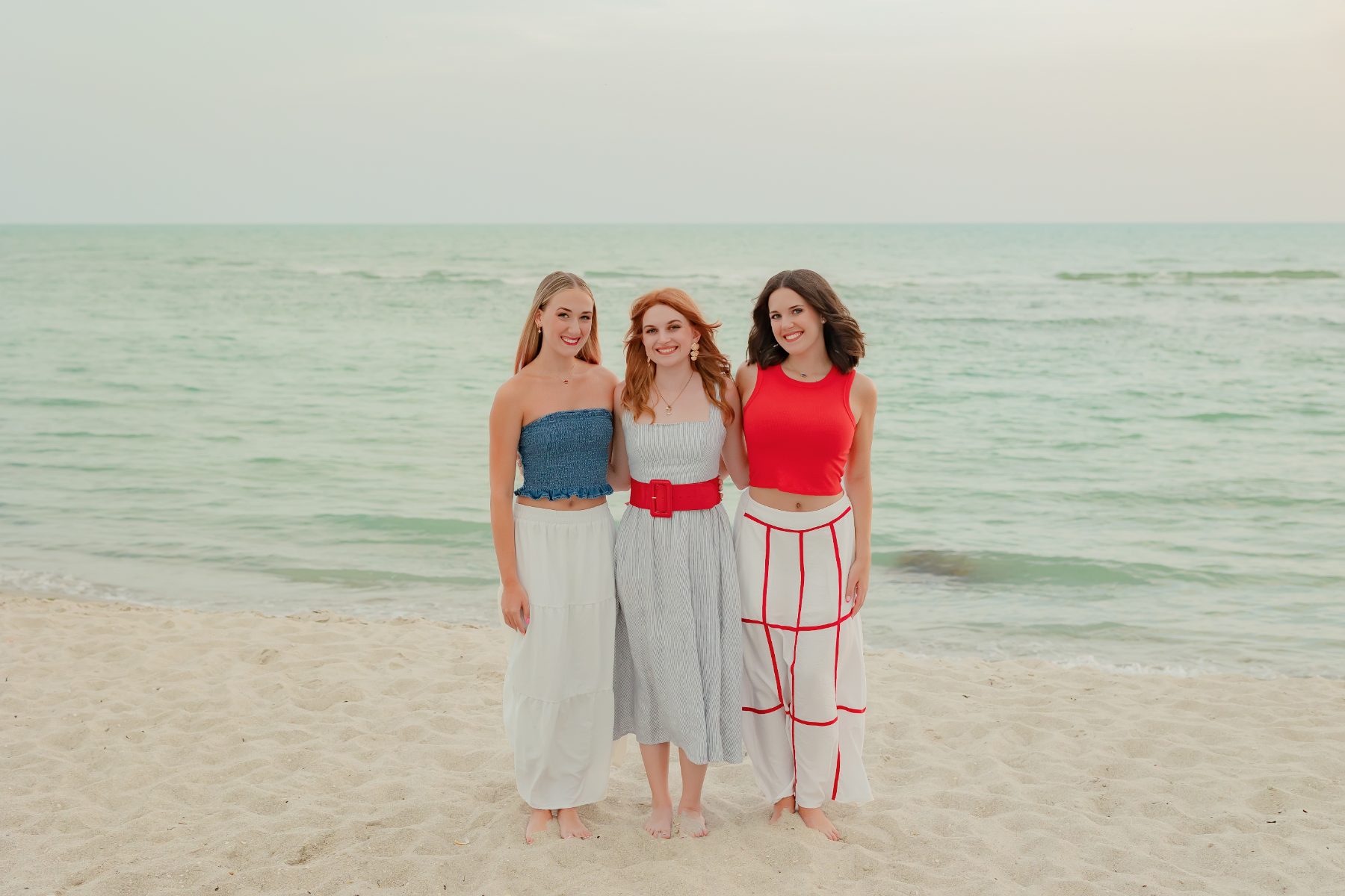 Three cousins pose seaside in blue, red and white