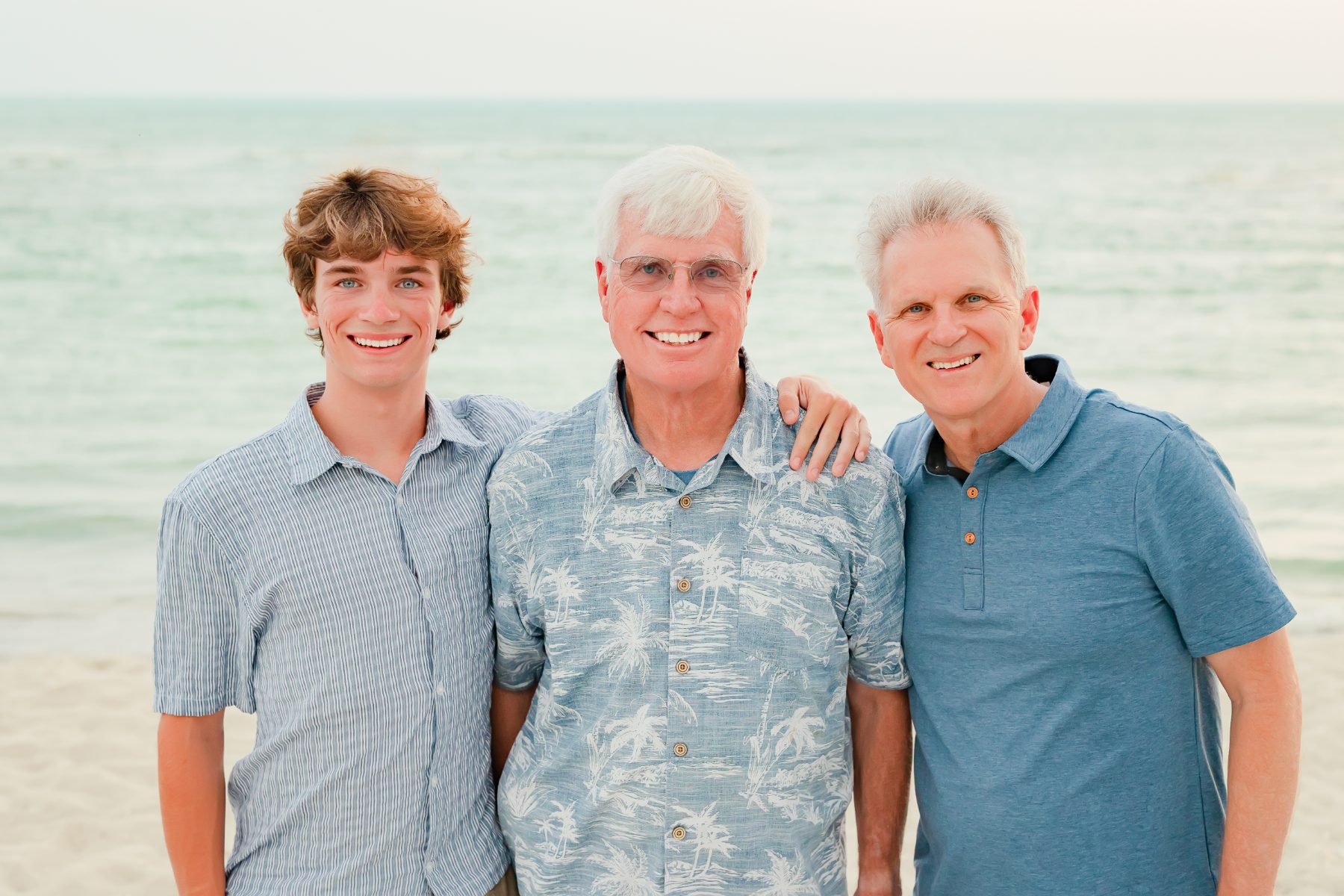 Grandfather, son and grandson pose together on Captiva Island beach