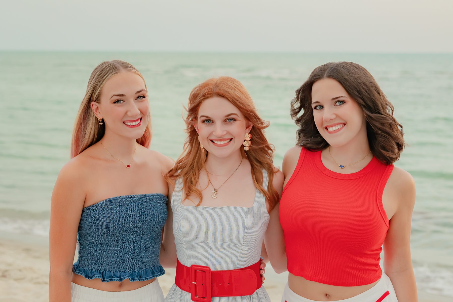 Three young women in colorful outfits smile together