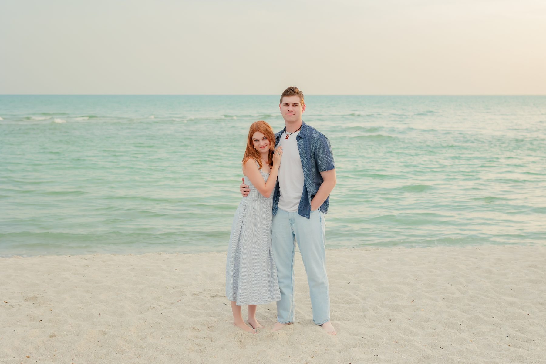 Young couple stands close on the sandy shoreline