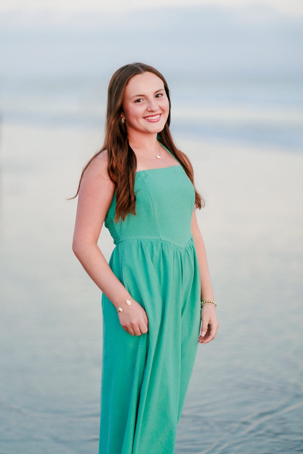 Smiling woman in green dress poses along the Coronado Beach shoreline
