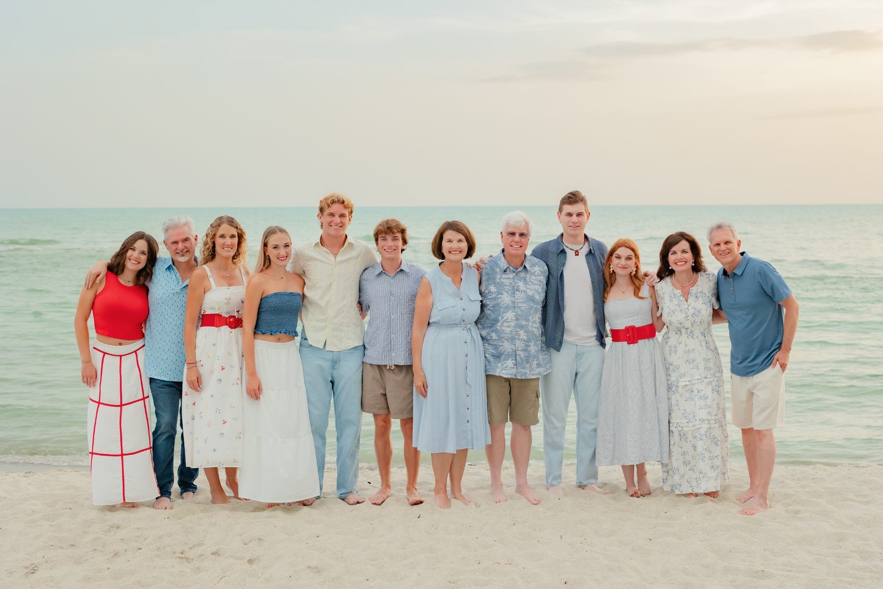 Whole extended family gathered smiling on the beach for reunion portrait