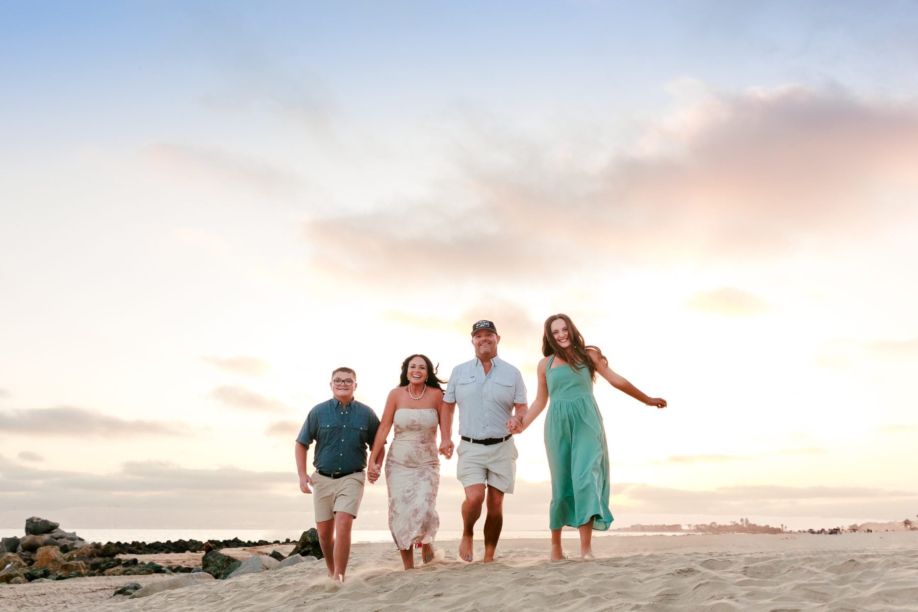 Family of four walks along sand dune at Hotel del Coronado sunset