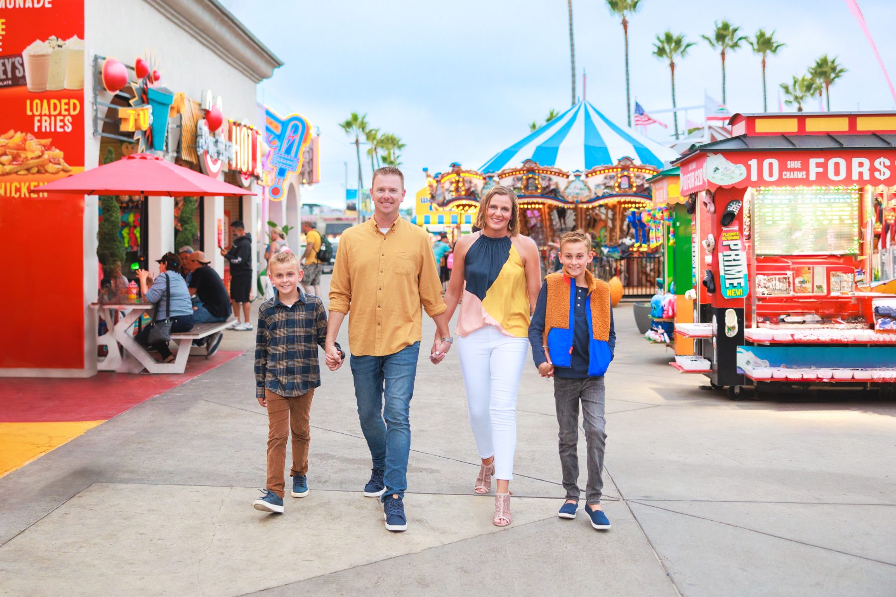 Family walking hand in hand through a colorful carnival midway at dusk