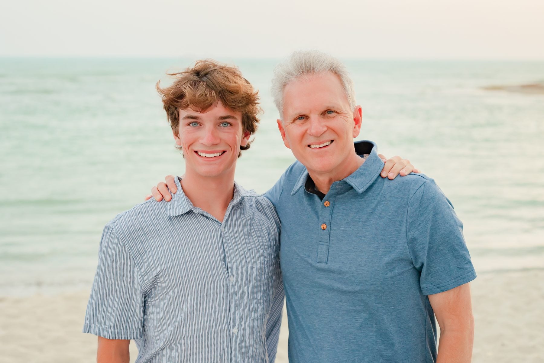 Father and teenage son smiling together on the Sanibel Island beach