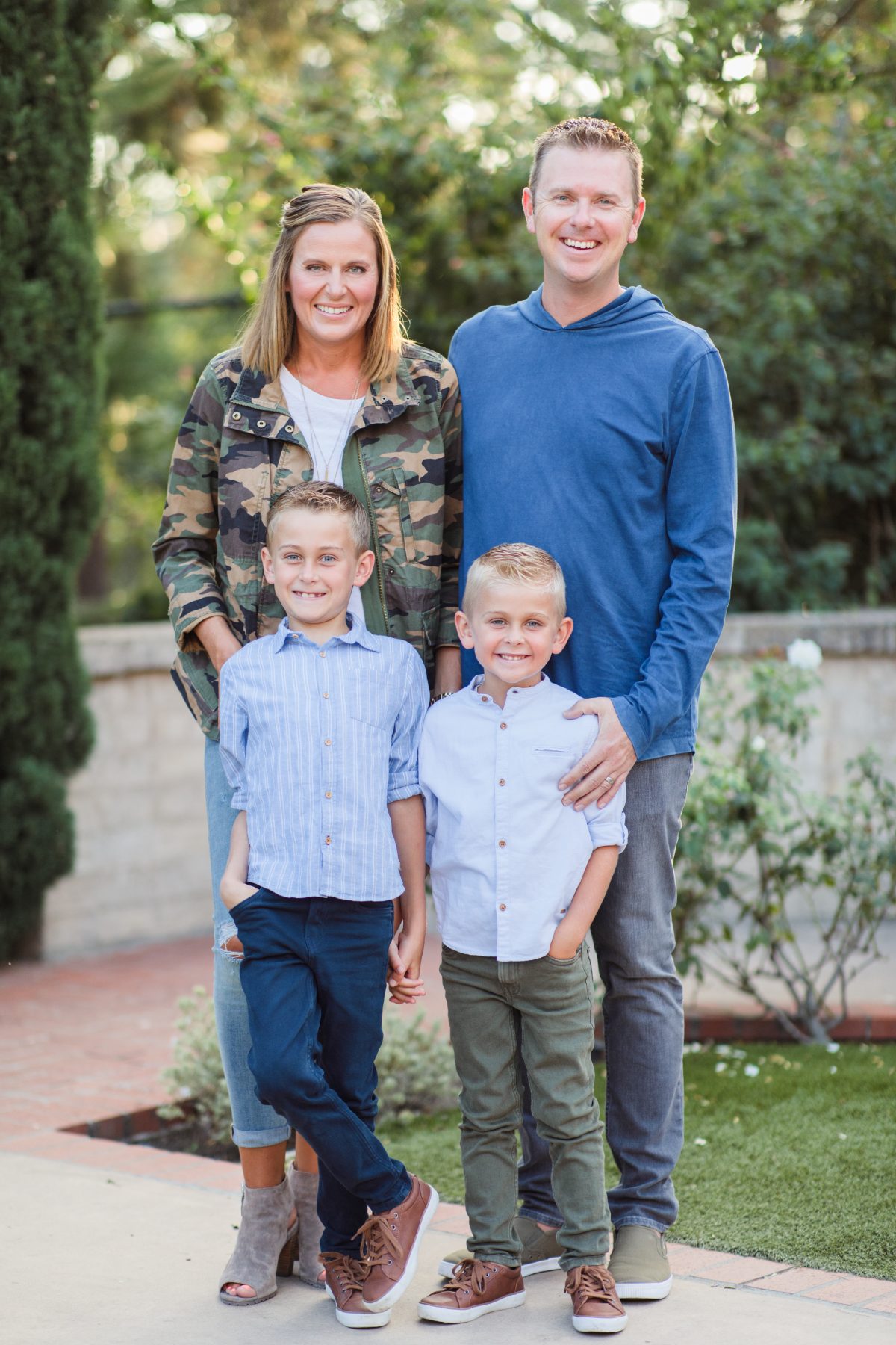 Parents and two sons pose in garden pathway, mom in camouflage jacket