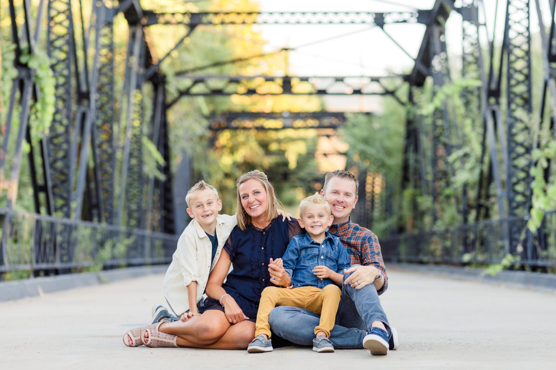 Family of five sits together on iron truss bridge for San Diego family photographer session