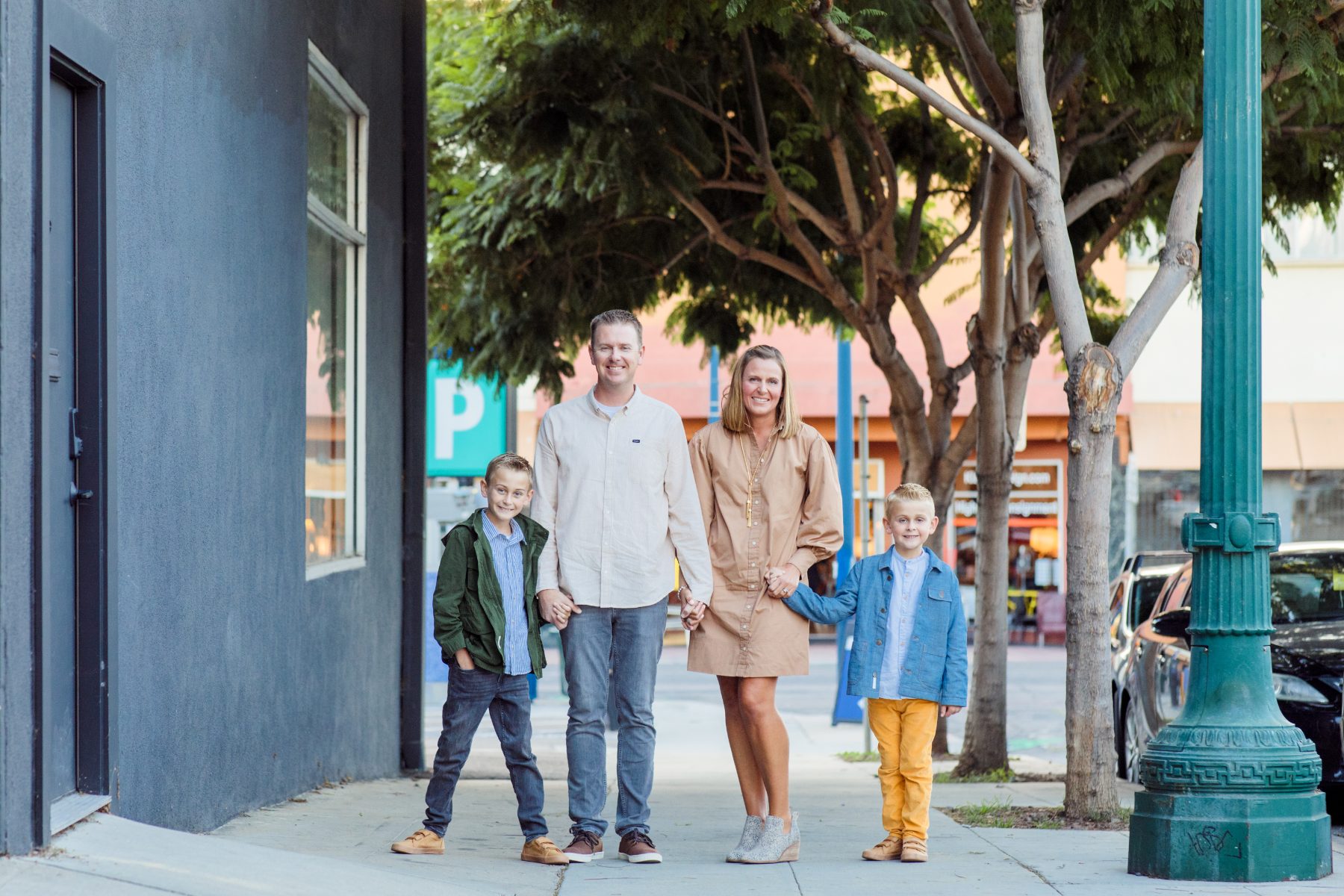 Family of four walks hand in hand along downtown San Diego sidewalk