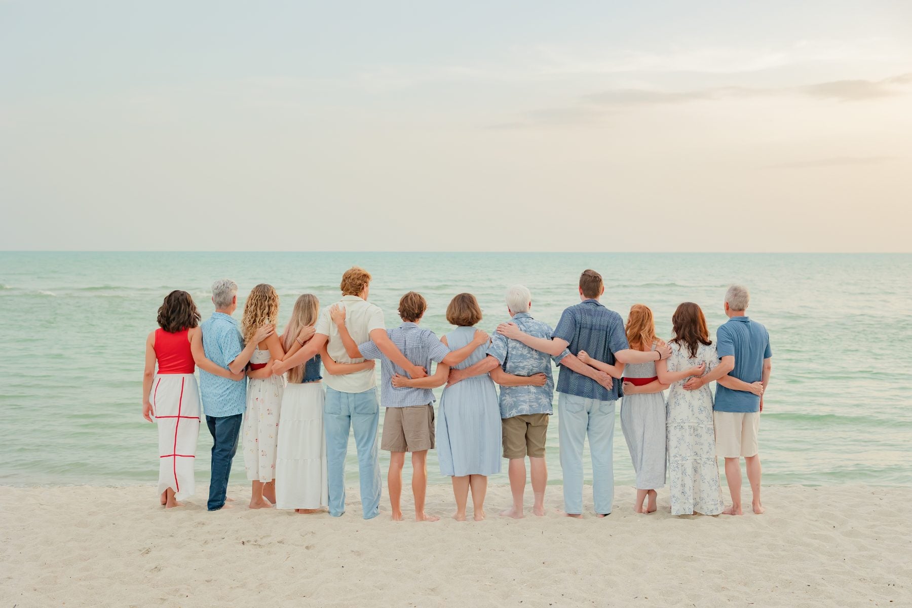 Family group linked arm-in-arm facing the ocean on Sanibel Island shore