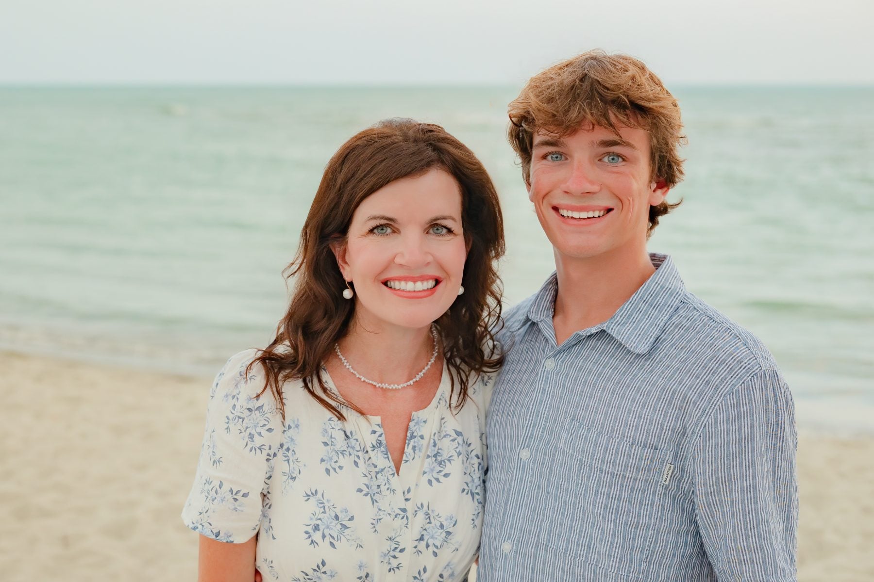 Mother and teenage son smile together on the Sanibel shoreline