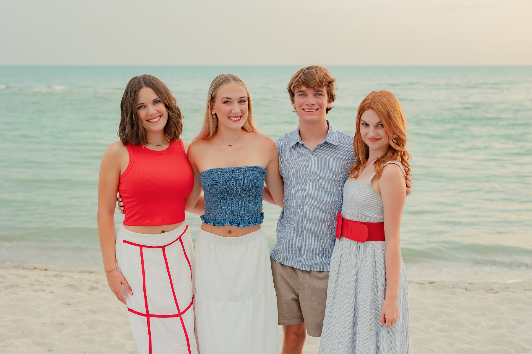 Four siblings pose together on the sand during Florida family reunion