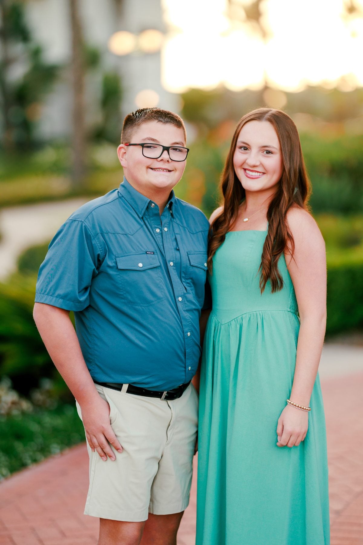 Brother and sister pose together in matching teal and blue outfits