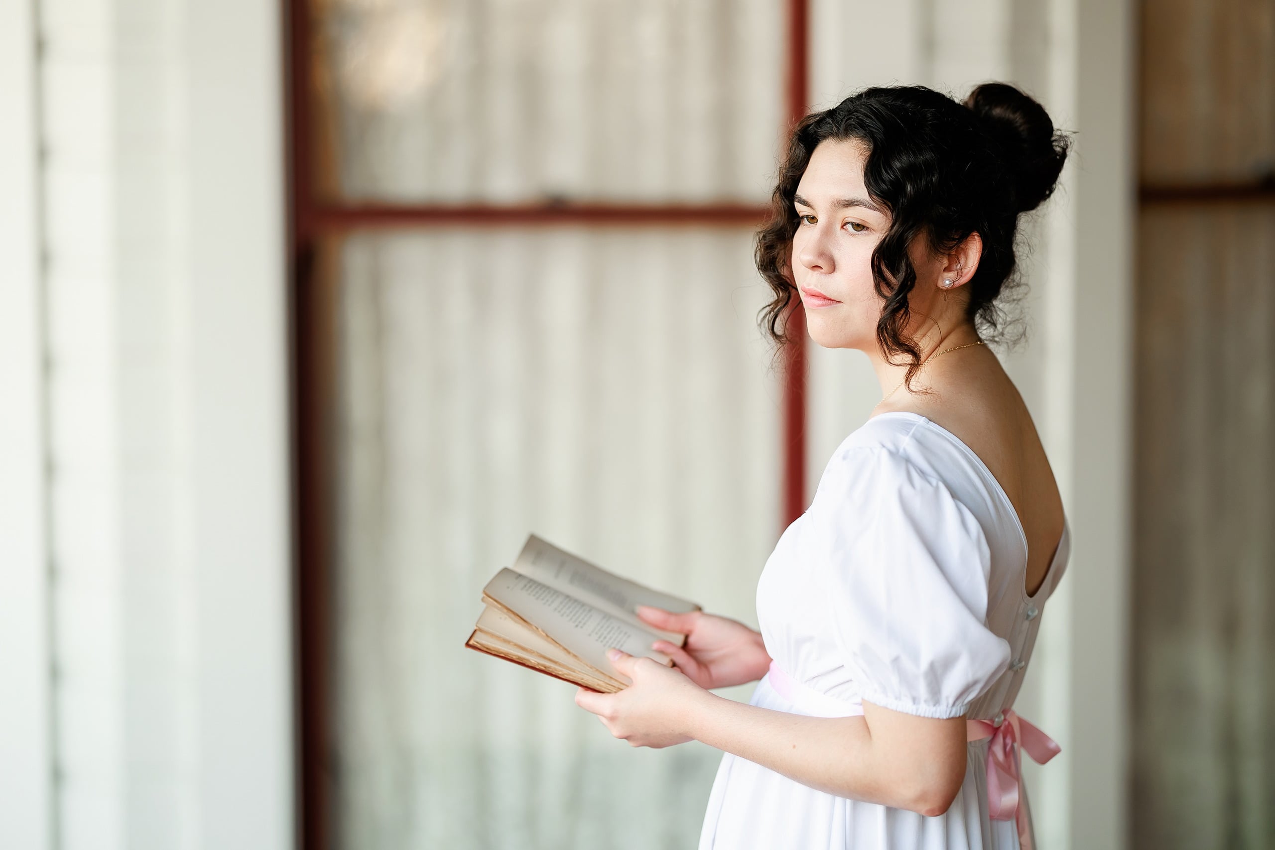 Amanda Fagan’s Love, Jane — 04 Woman in white dress holding open book, looking back over shoulder