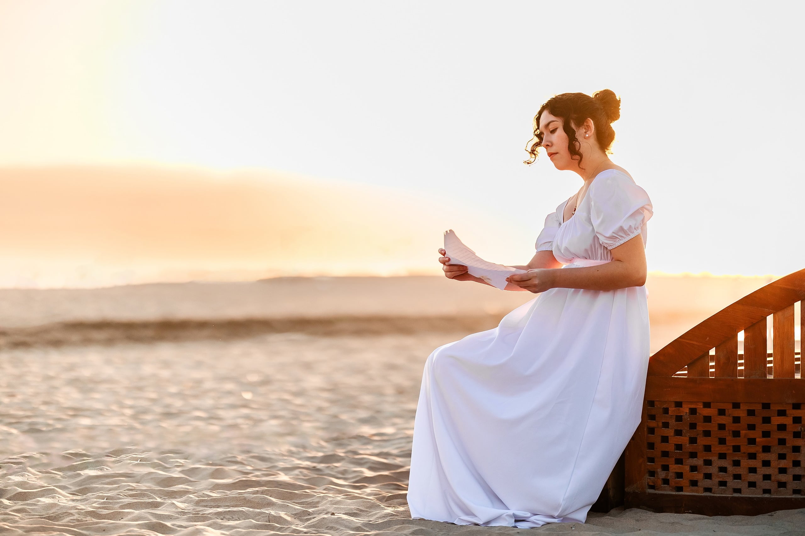 Amanda Fagan’s Love, Jane — 13 Woman in white dress sitting on wooden pier holding documents at sunset