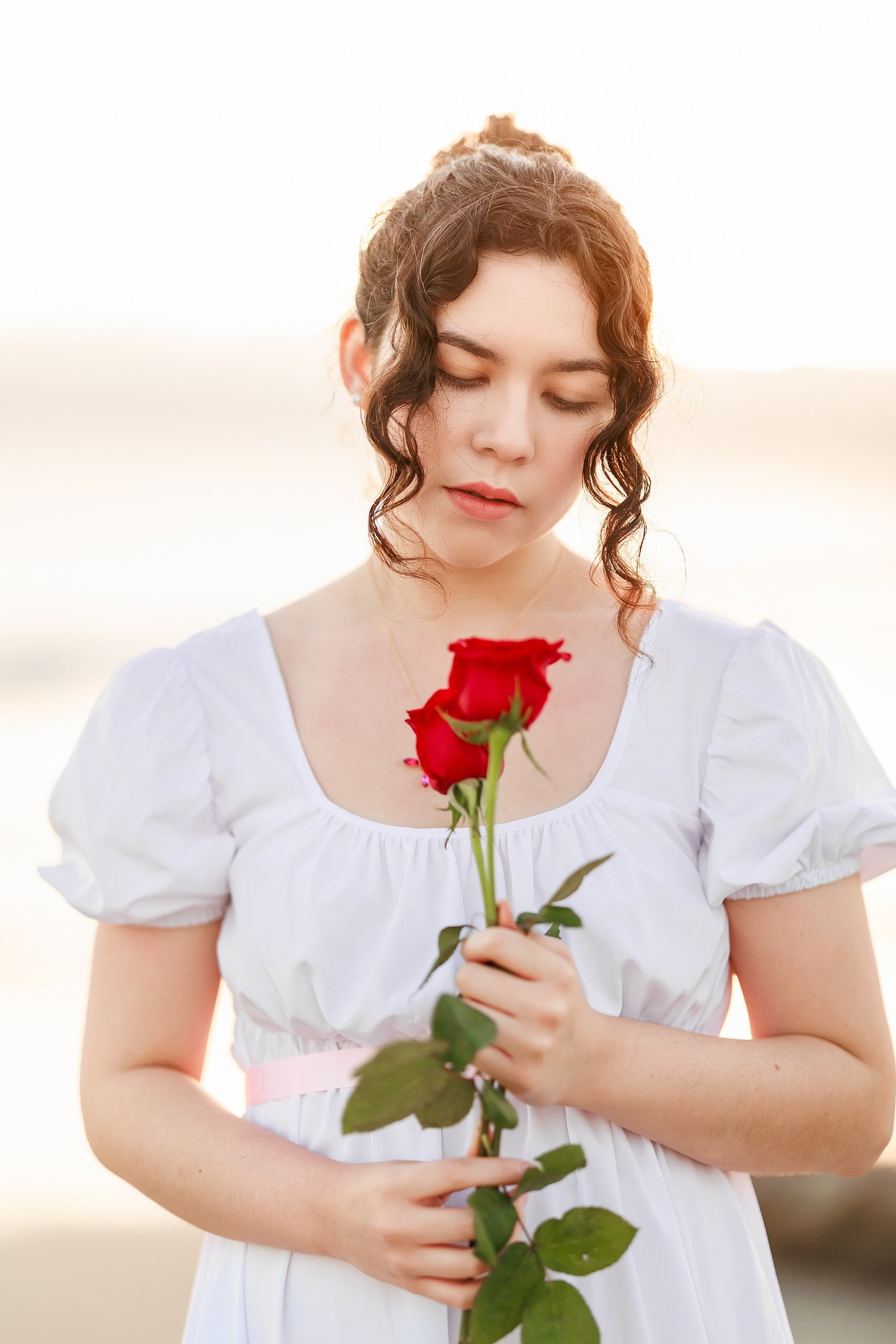 Amanda Fagan’s Love, Jane — 15 Woman holding red rose close-up, looking down at beach with ocean beyond