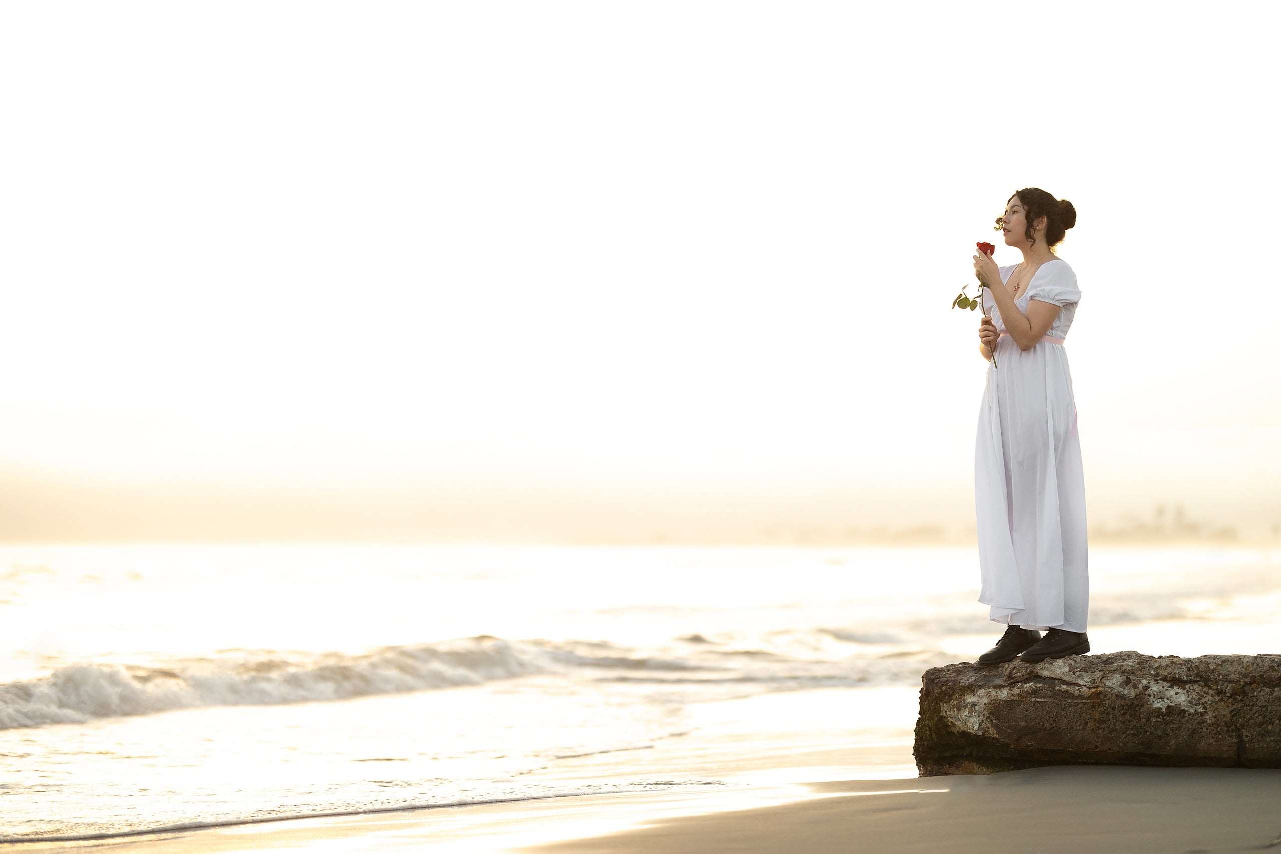 Amanda Fagan’s Love, Jane — 18 Woman in white dress holding yellow flowers on rock in ocean at golden hour