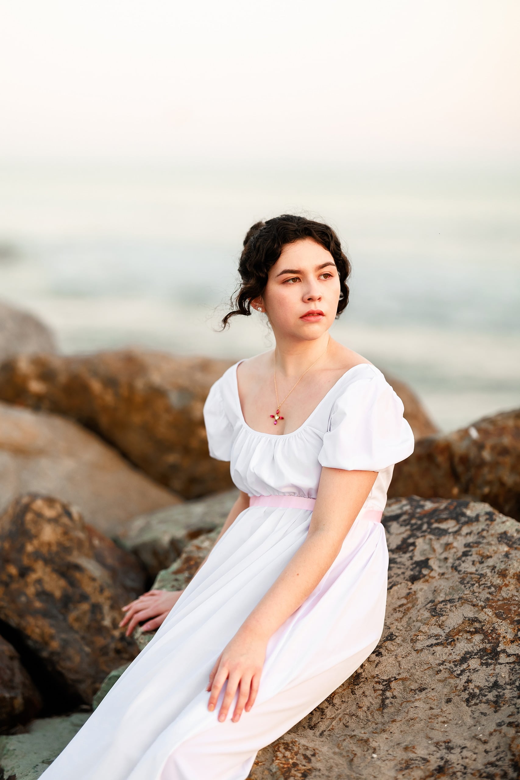 Amanda Fagan’s Love, Jane — 19 Woman in white dress reclining on rocky beach formation looking at camera