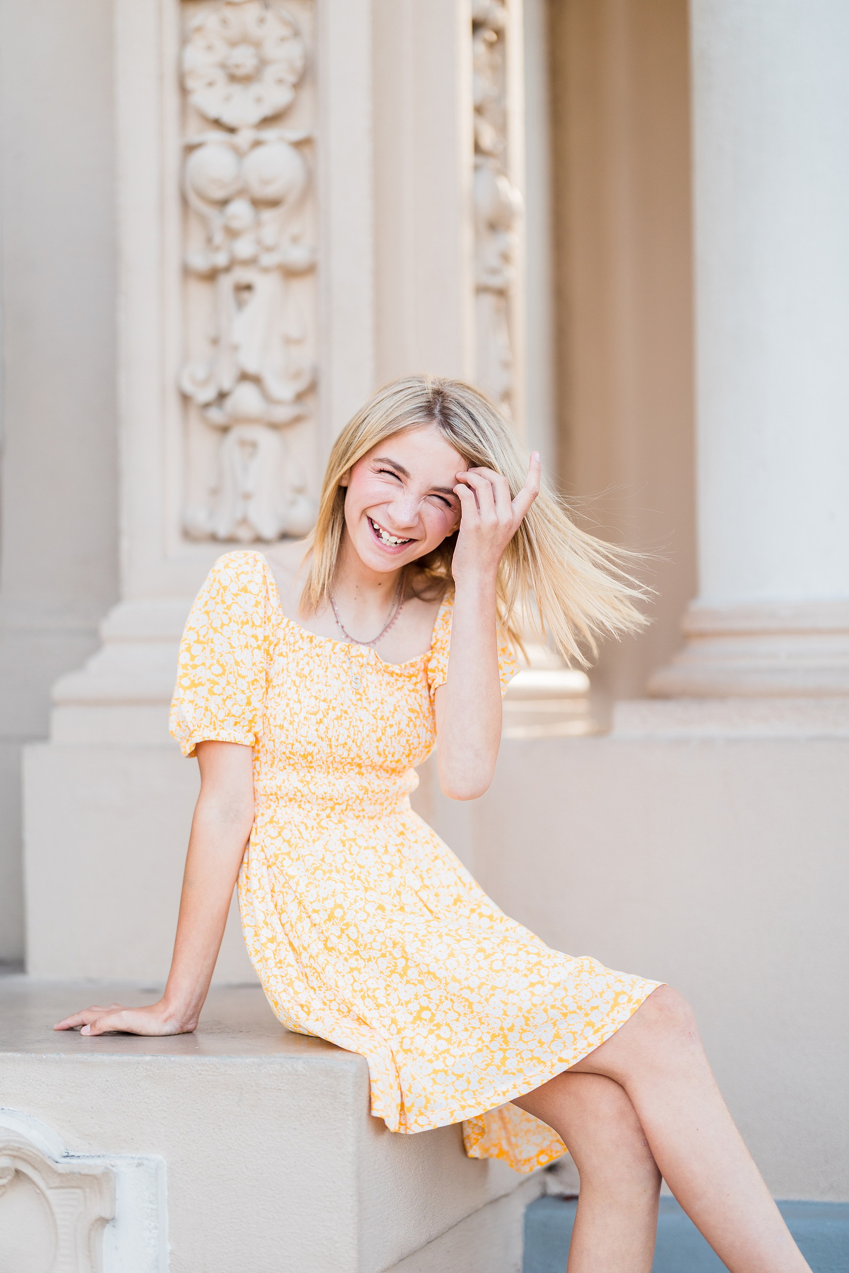 Balboa Park Family Portraits San Diego — 02 Girl in yellow dress seated on ledge, hand in hair, at Balboa Park