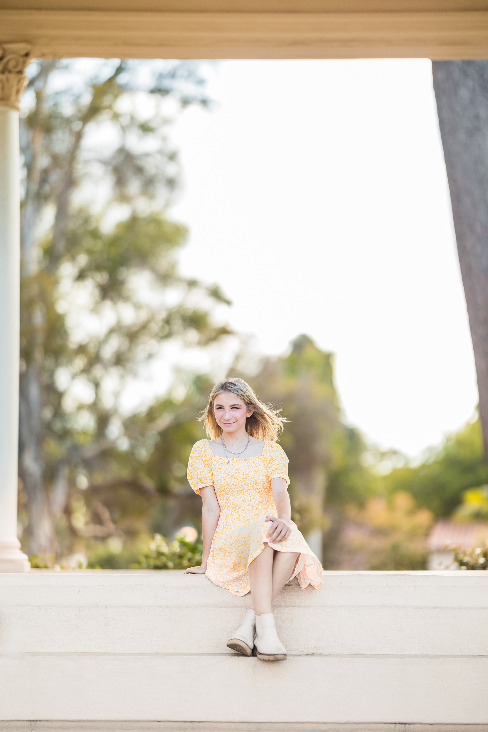 Balboa Park Family Portraits San Diego — 03 Sophie sitting on ledge beneath arches at Balboa Park, wearing yellow