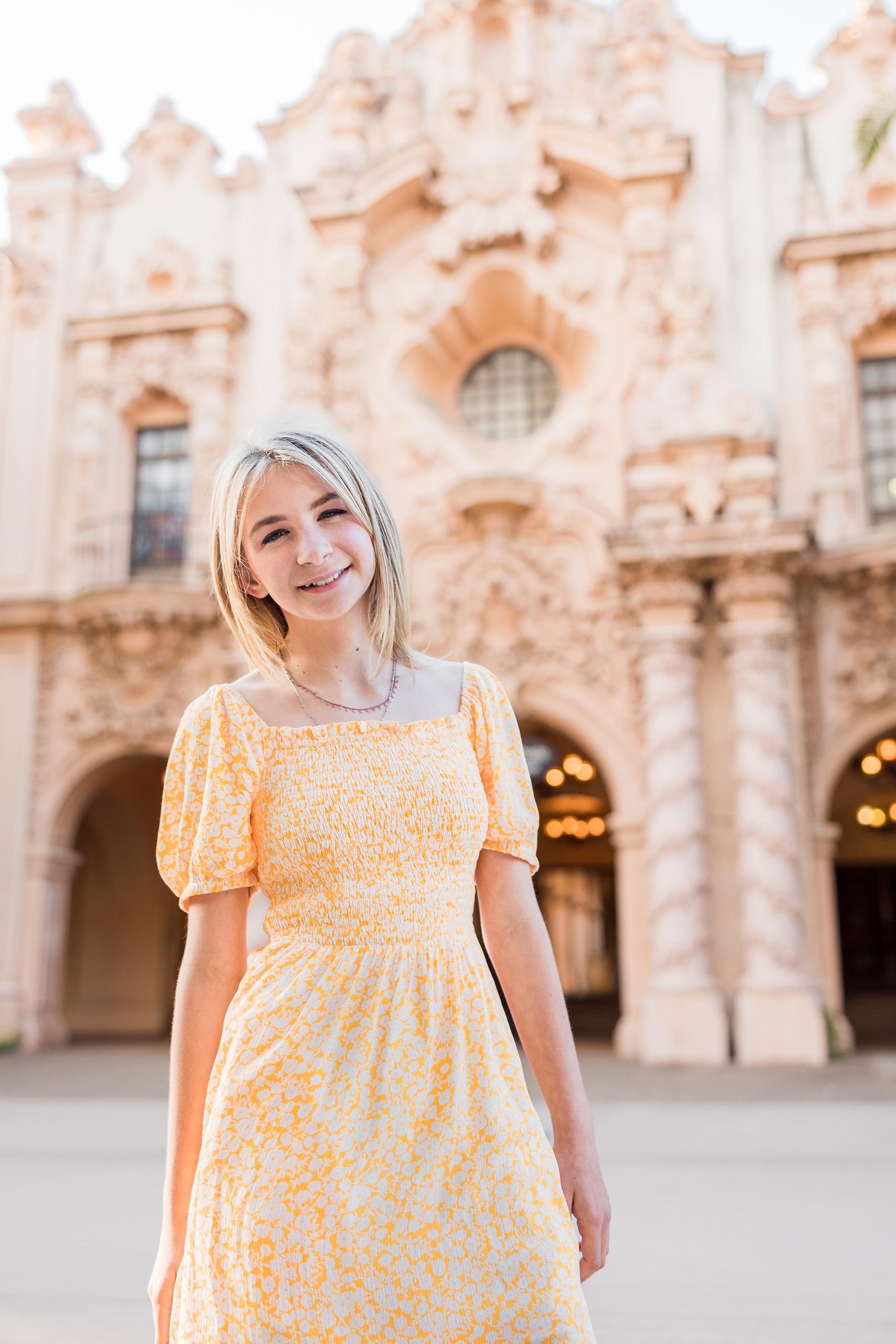 Balboa Park Family Portraits San Diego — 25 Woman standing and reaching toward yellow roses in Balboa Park garden