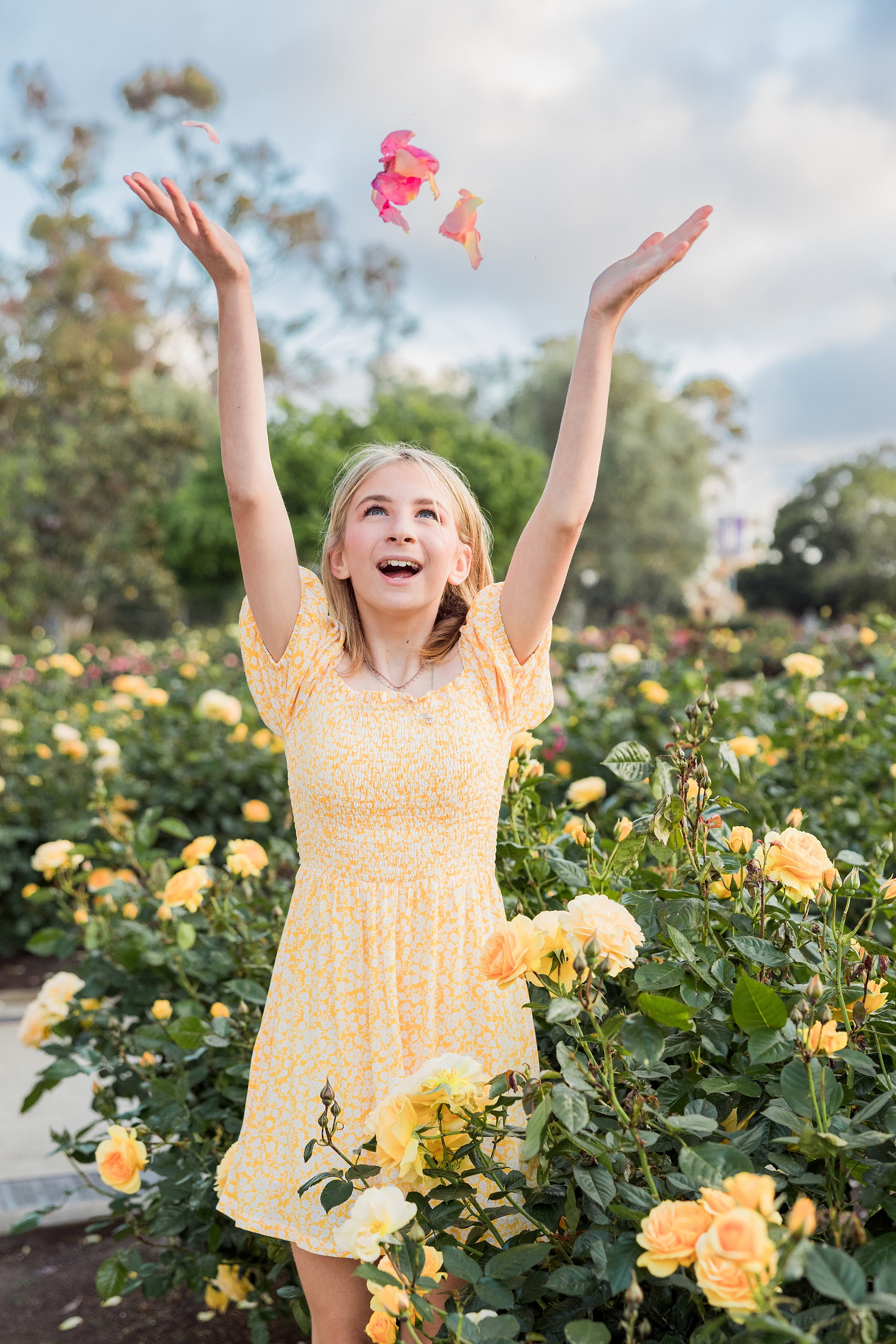 Balboa Park Family Portraits San Diego — 27 Sophie with arms raised tossing petals amid flowers at Balboa Park