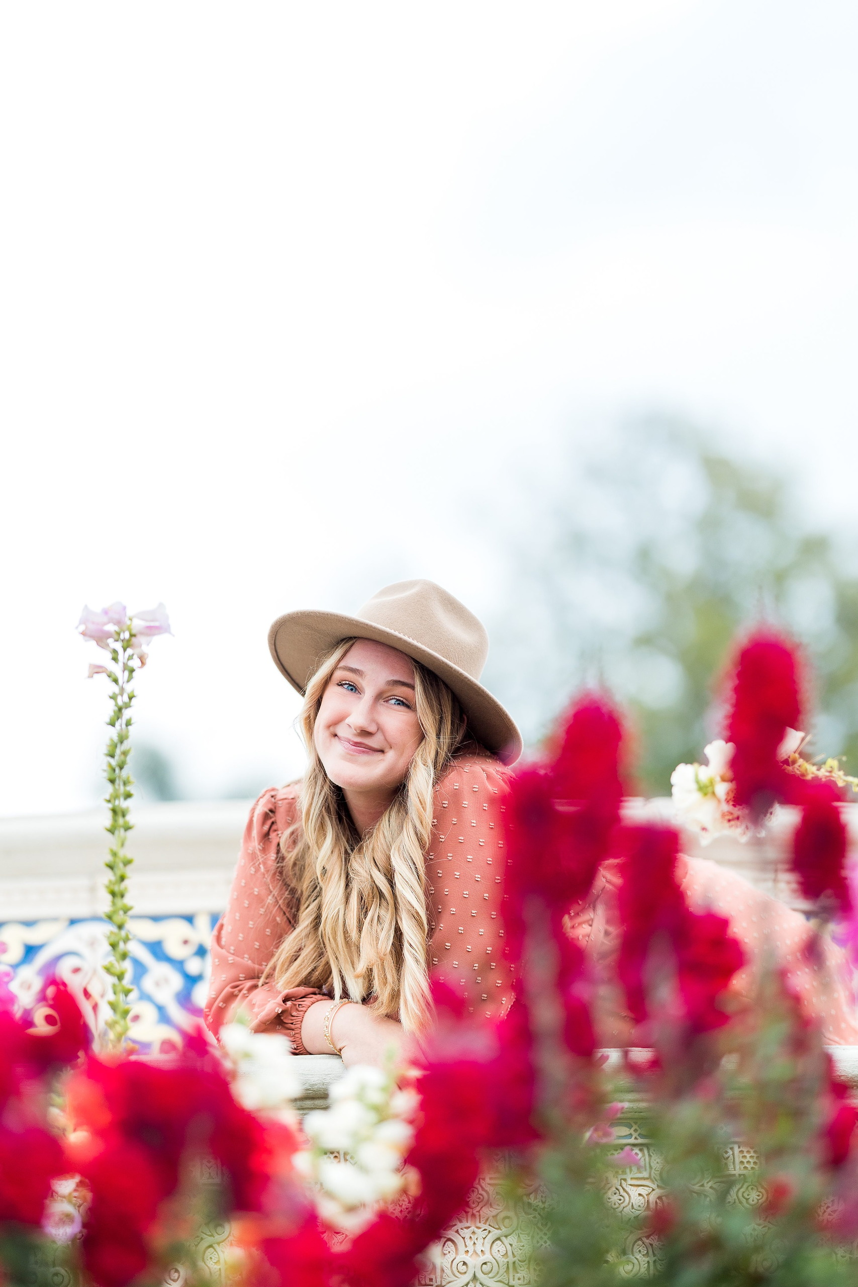 Balboa Park Senior Photography Session — 08 Senior standing with arms outstretched laughing among tall red flowering plants