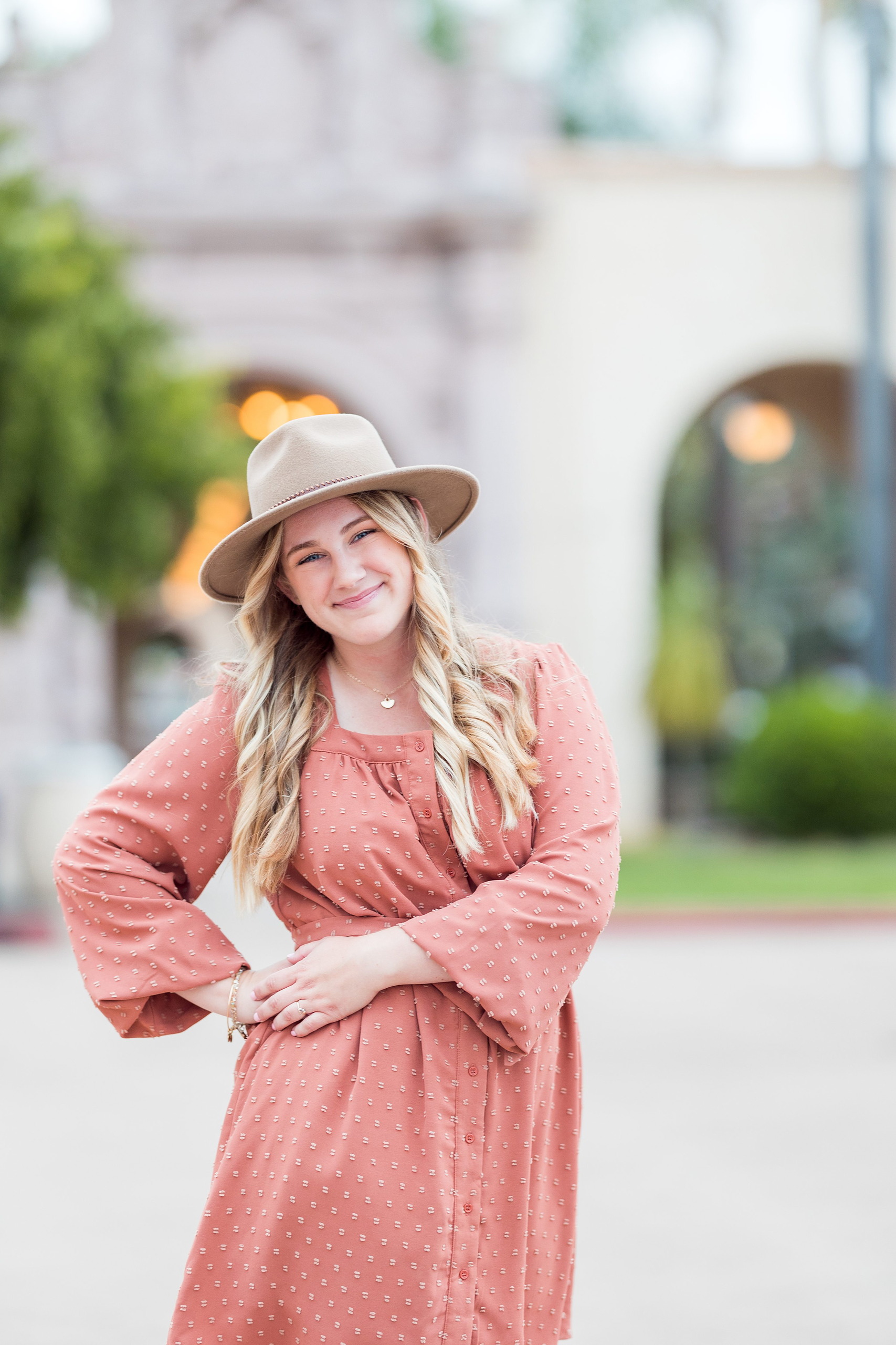 Balboa Park Senior Photography Session — 11 Senior at Balboa Park standing near white arched colonnade with flowering plants nearby
