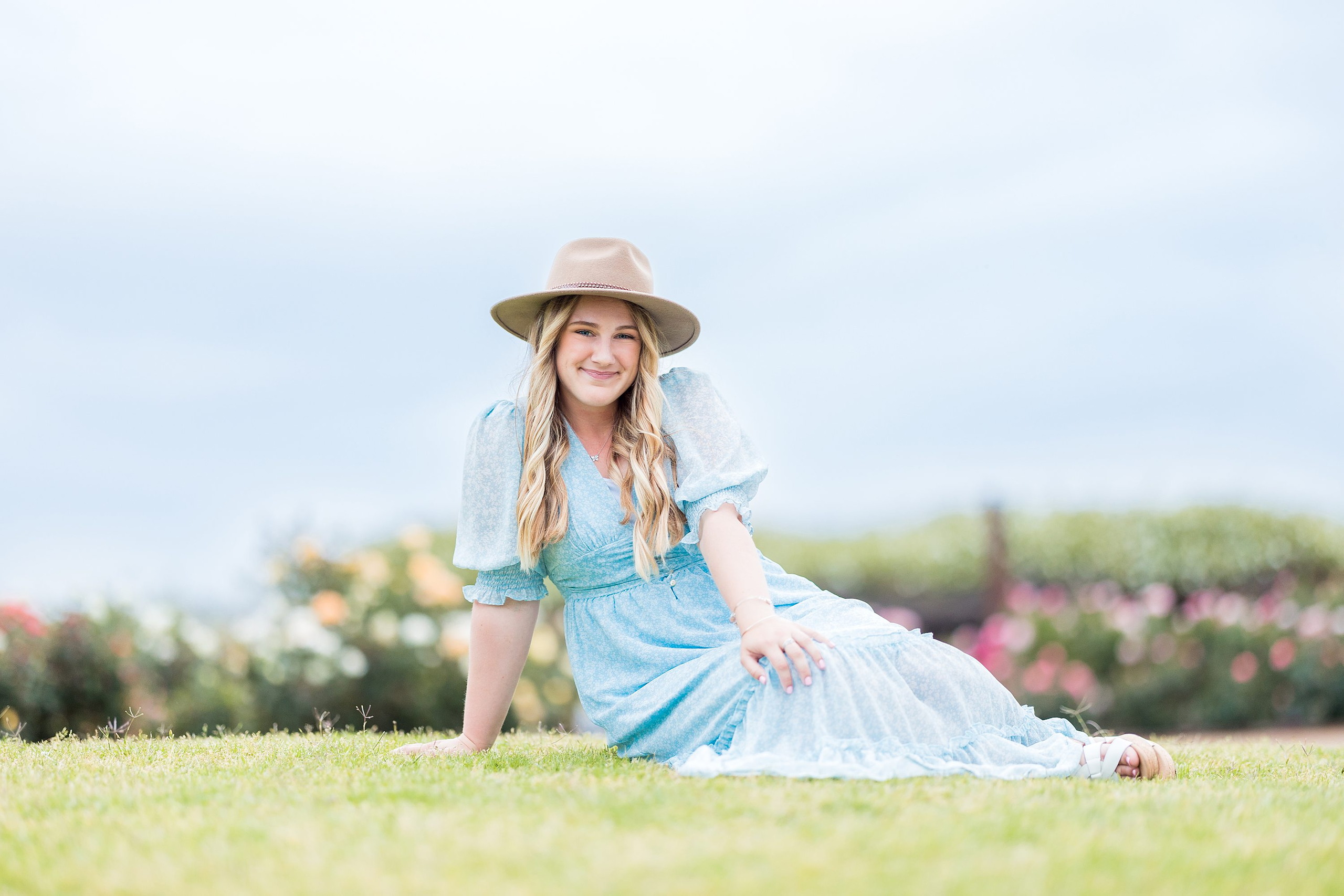 Balboa Park Senior Photography Session — 19 Senior in blue dress wearing round sunglasses sitting on stone bench at park