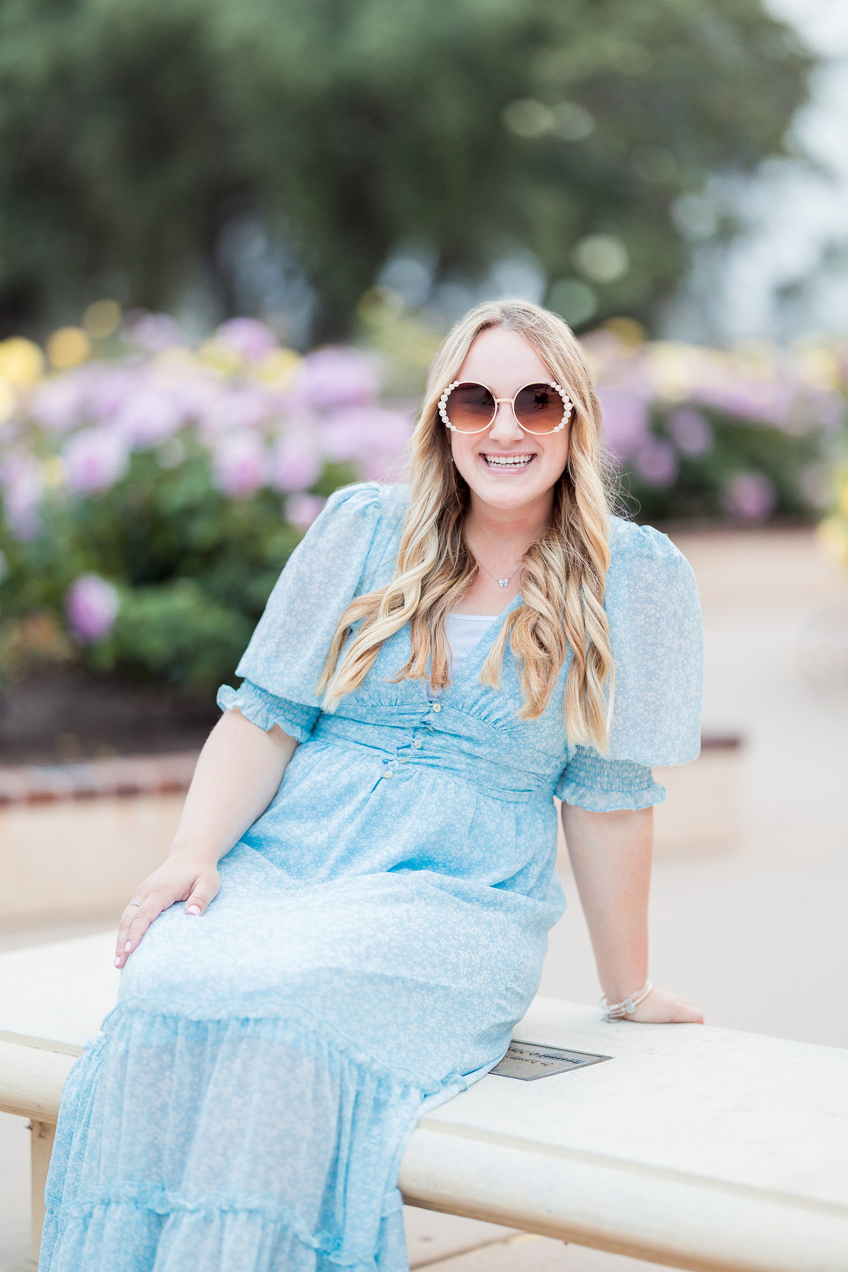 Balboa Park Senior Photography Session — 20 Senior holding up blue graduation cap, pink top with white dots, colorful backdrop