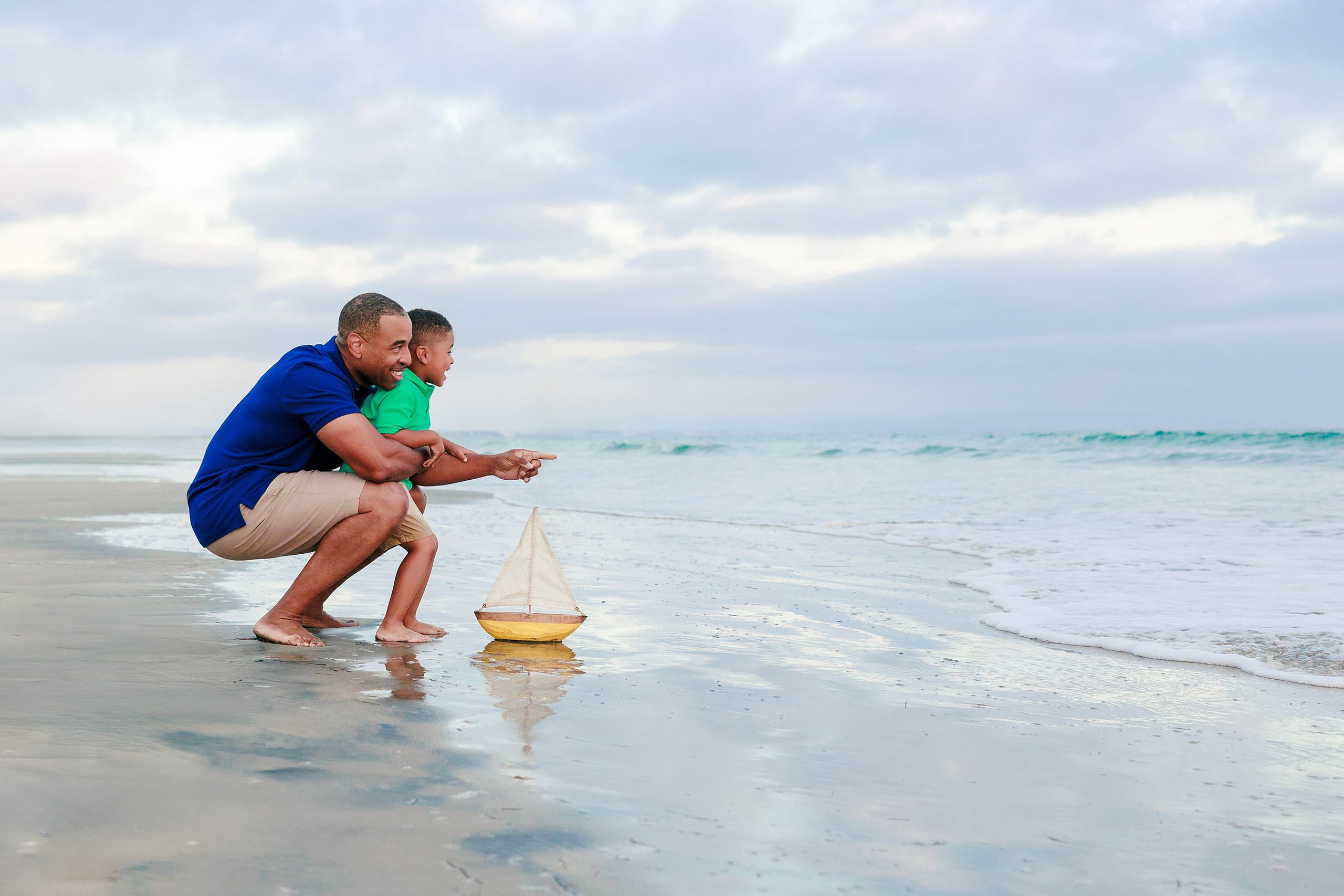 Because Time Flies: Family Photos on Coronado — 24 Dion crouches down with his son beside a toy boat in the water