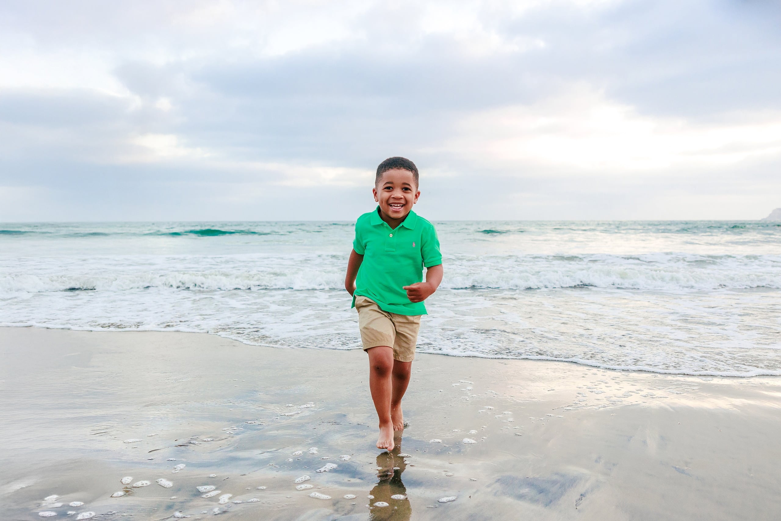 Because Time Flies: Family Photos on Coronado — 25 Younger son in green runs alone along the sand on Coronado beach