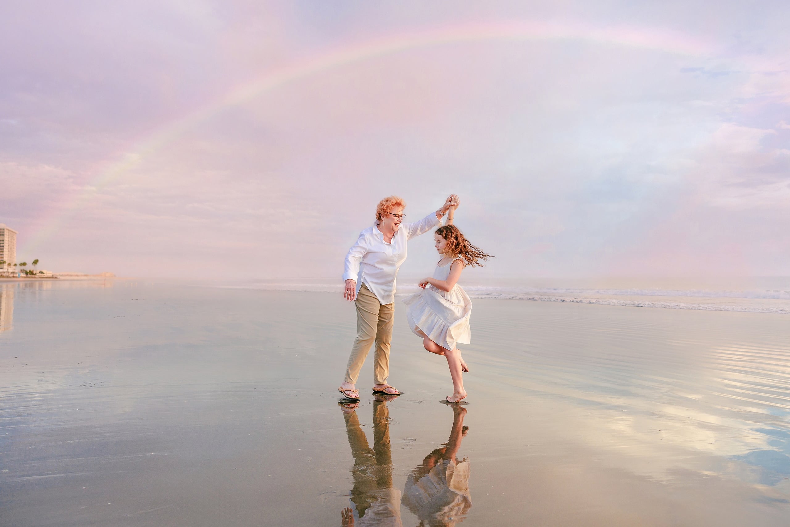 Behind the Scenes of Grammy Judy’s 80th Birthday Session: An Interview with Wendy — 13 Man and girl dance together on beach at golden hour, both in motion with pink sky