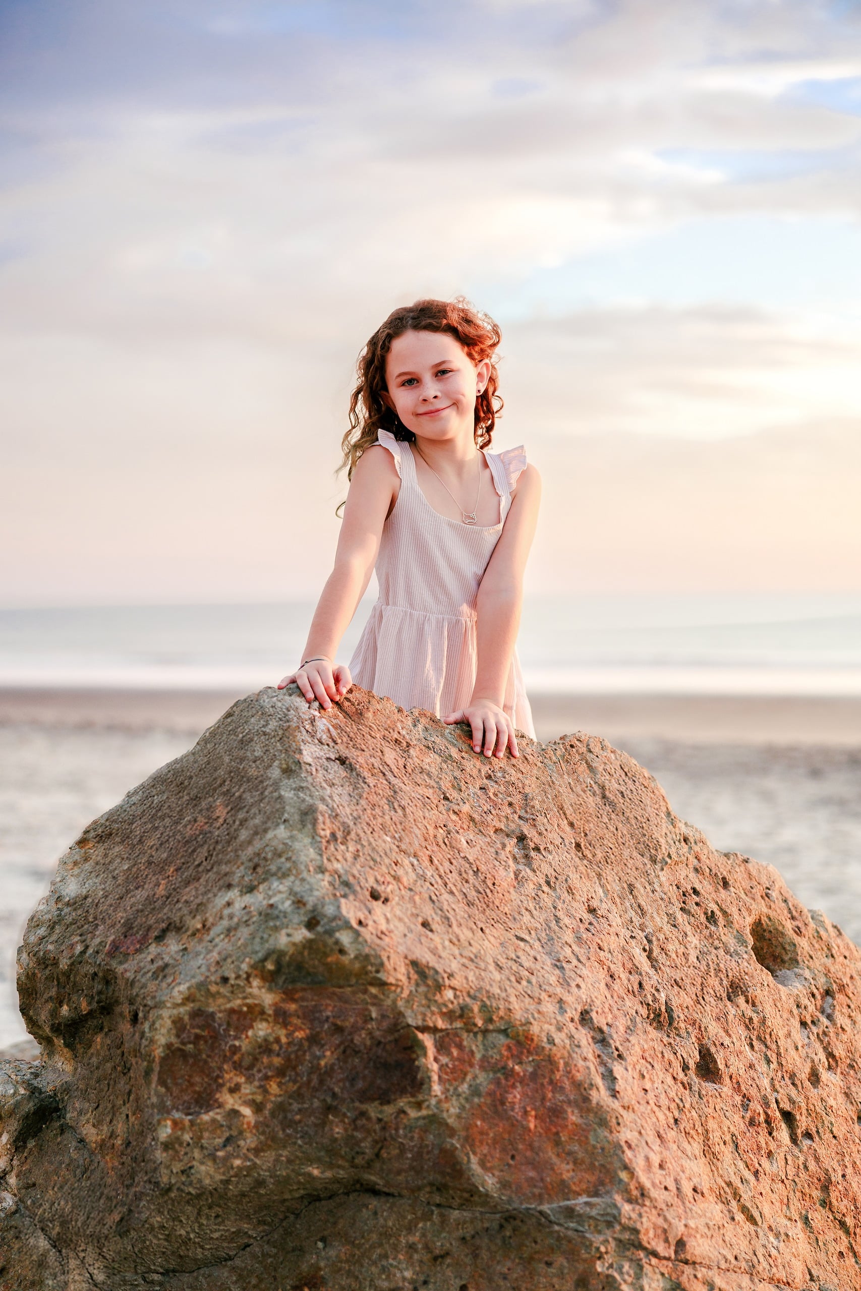 Behind the Scenes of Grammy Judy’s 80th Birthday Session: An Interview with Wendy — 14 Girl sits on large rock in lavender dress, hands resting on stone as sun sets
