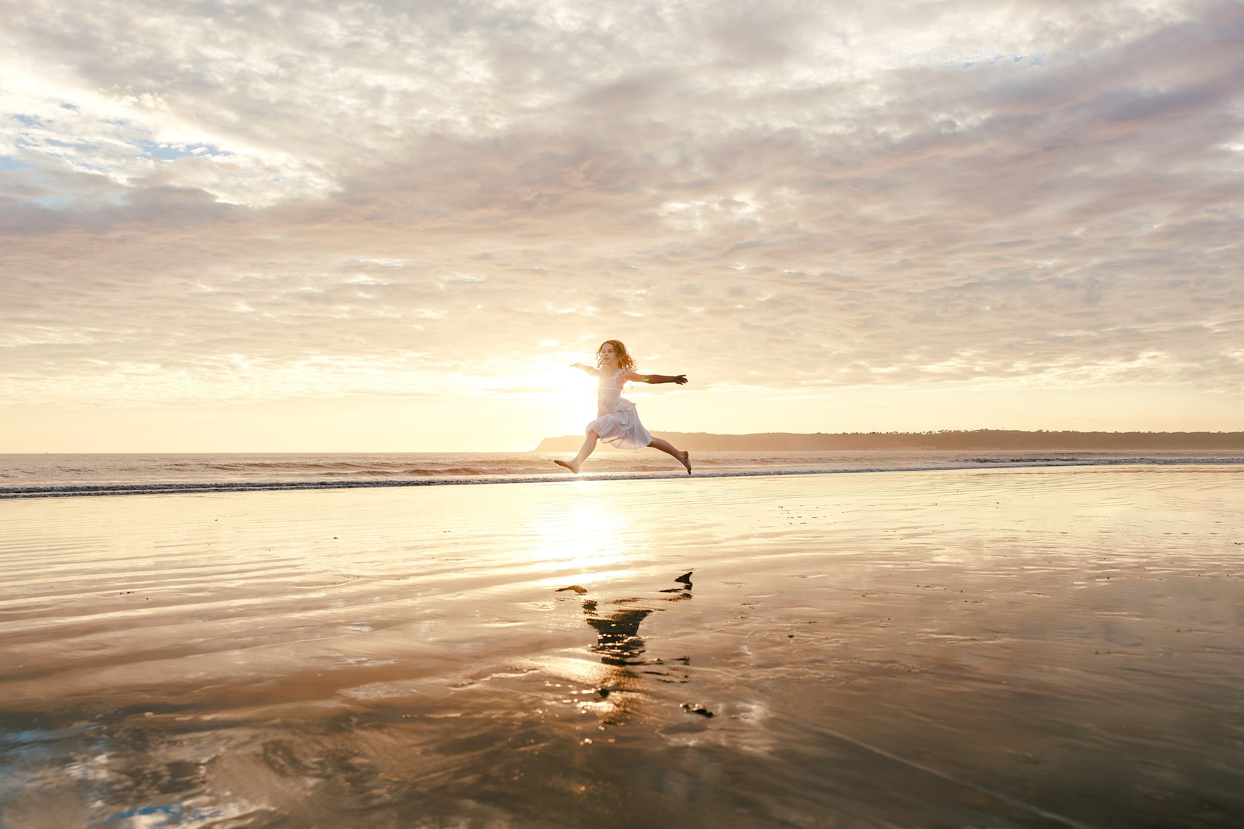 Behind the Scenes of Grammy Judy’s 80th Birthday Session: An Interview with Wendy — 15 Girl in white dress stretches in a lunge across wet sand at golden hour sunset