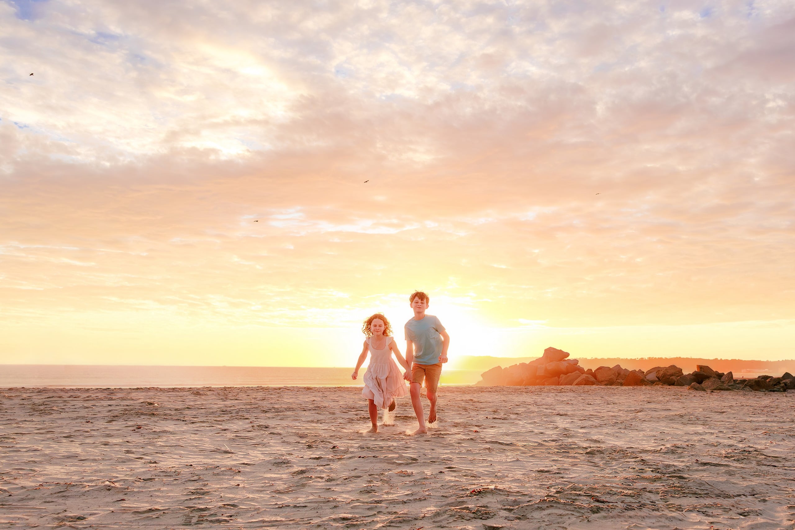 Behind the Scenes of Grammy Judy’s 80th Birthday Session: An Interview with Wendy — 17 Boy in turquoise and girl in white walk together on beach at golden sunset