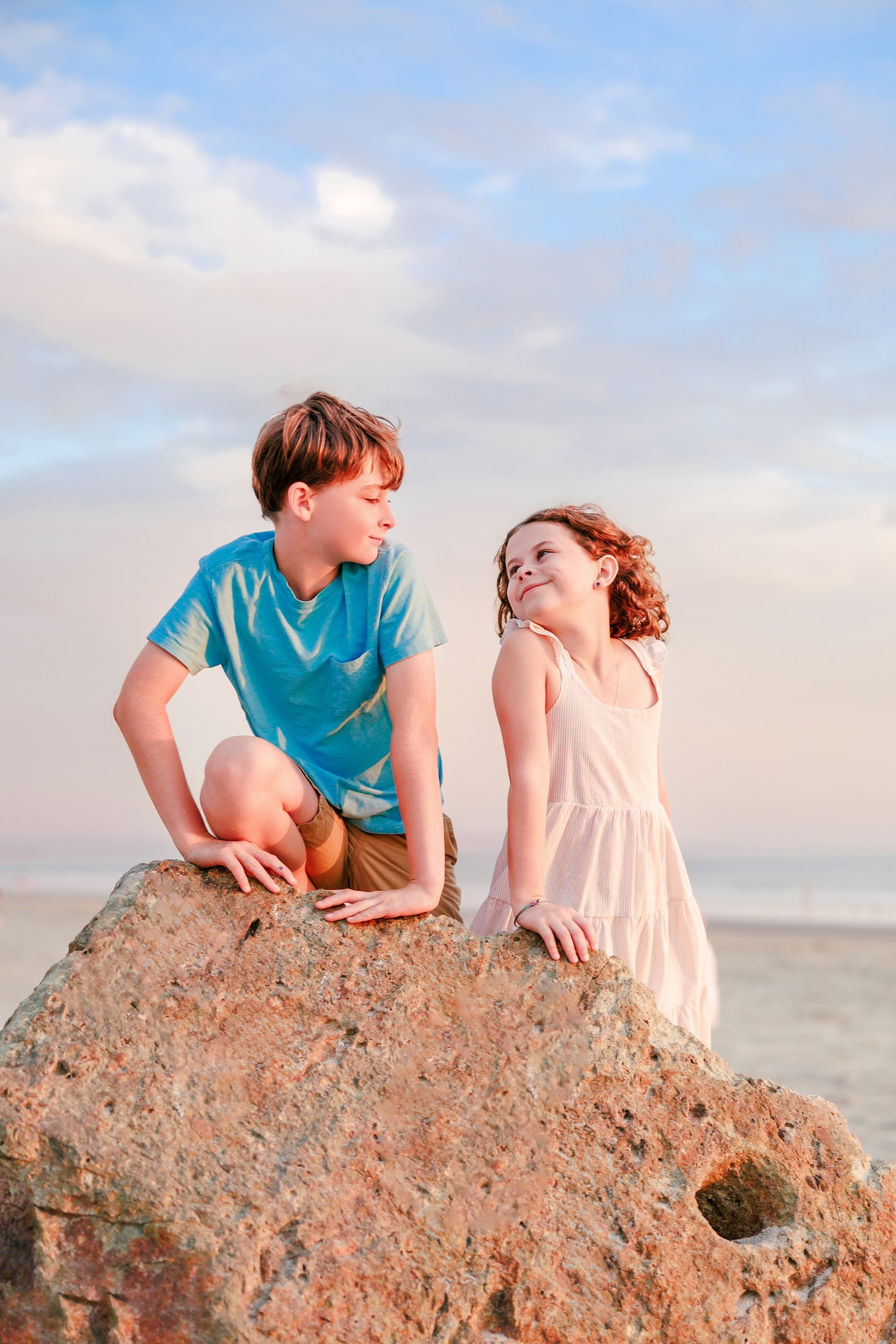 Behind the Scenes of Grammy Judy’s 80th Birthday Session: An Interview with Wendy — 22 Two children sit on rock looking in different directions, backlit by soft beach light