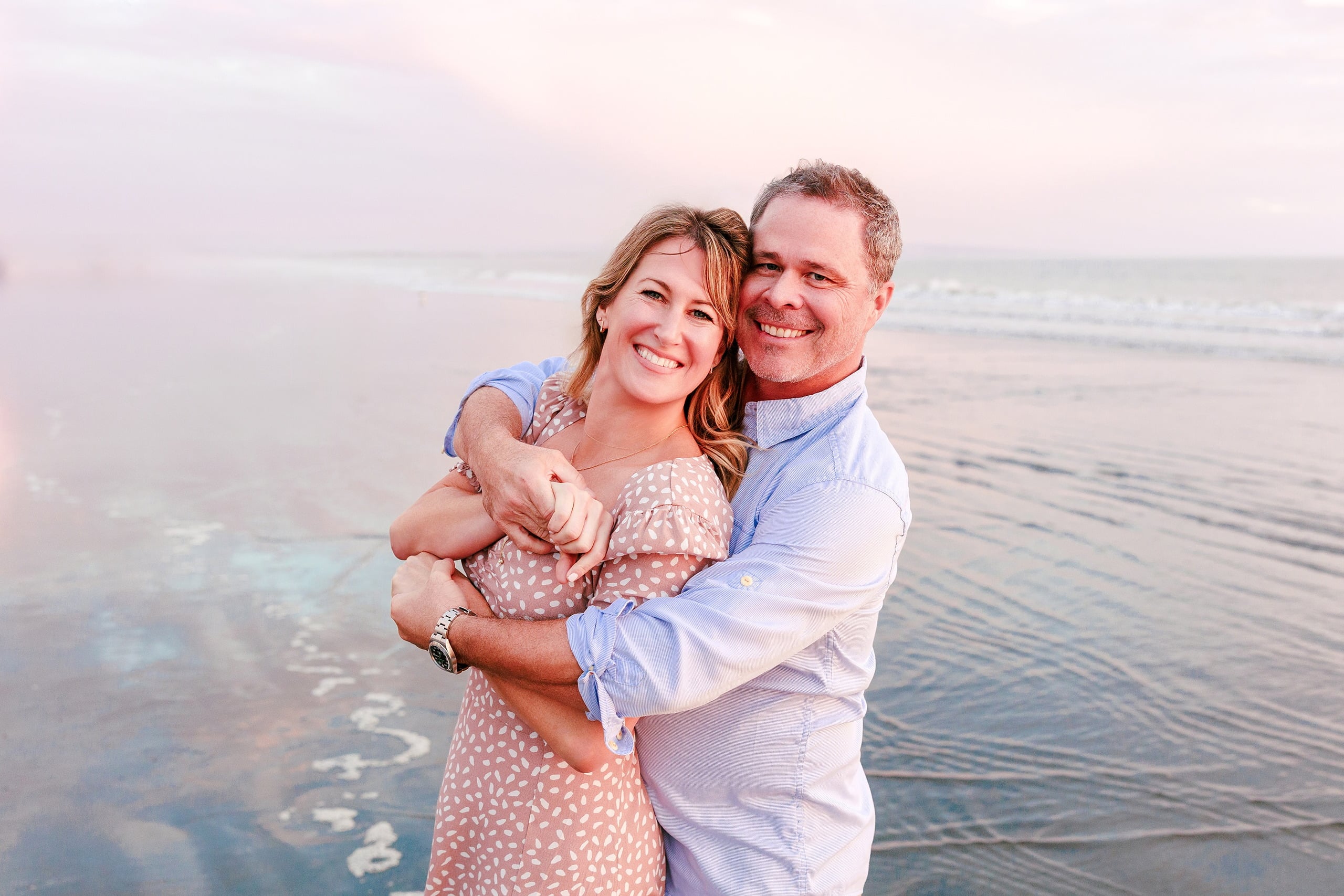 Behind the Scenes of Grammy Judy’s 80th Birthday Session: An Interview with Wendy — 26 Woman and man embrace each other on beach during soft golden hour light