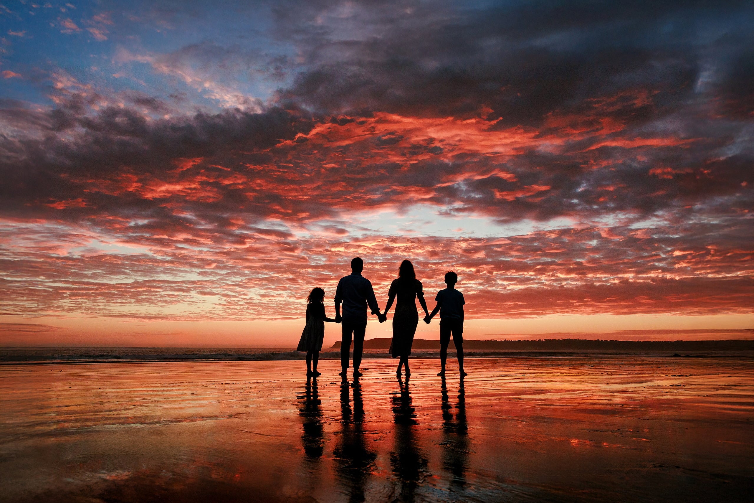 Behind the Scenes of Grammy Judy’s 80th Birthday Session: An Interview with Wendy — 31 Family of five silhouetted holding hands on wet sand during dramatic orange and red sunset