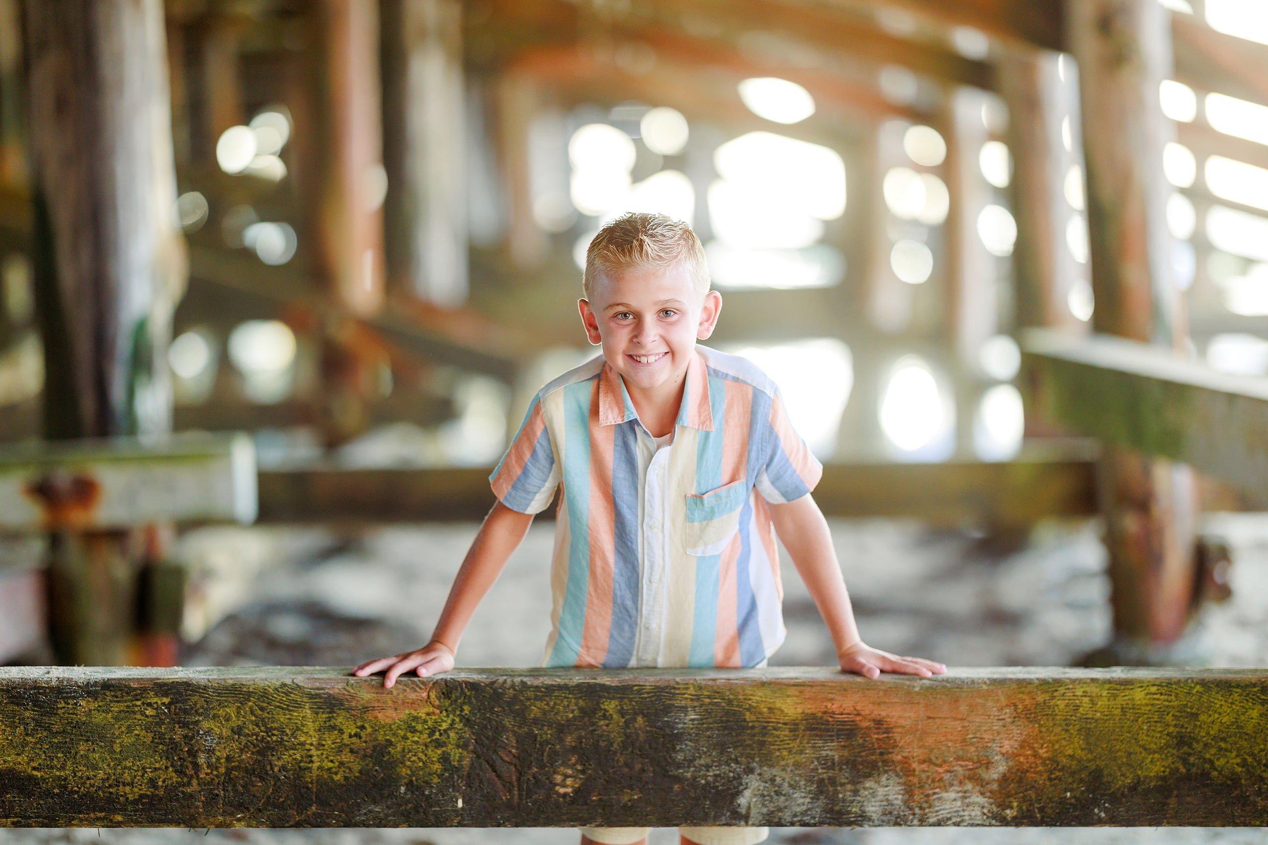 Butlers on the Beach — 07 Child in blue and orange striped shirt leaning against pier rail