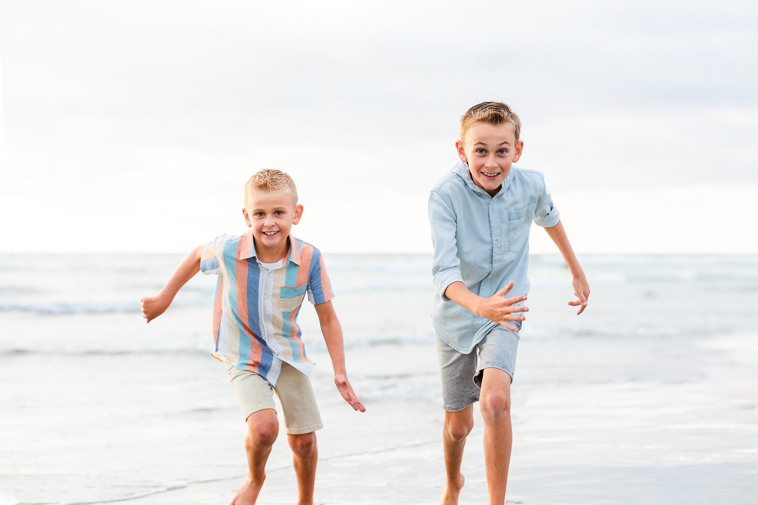 Butlers on the Beach — 10 Two children in light blue shirts running together through shallow water
