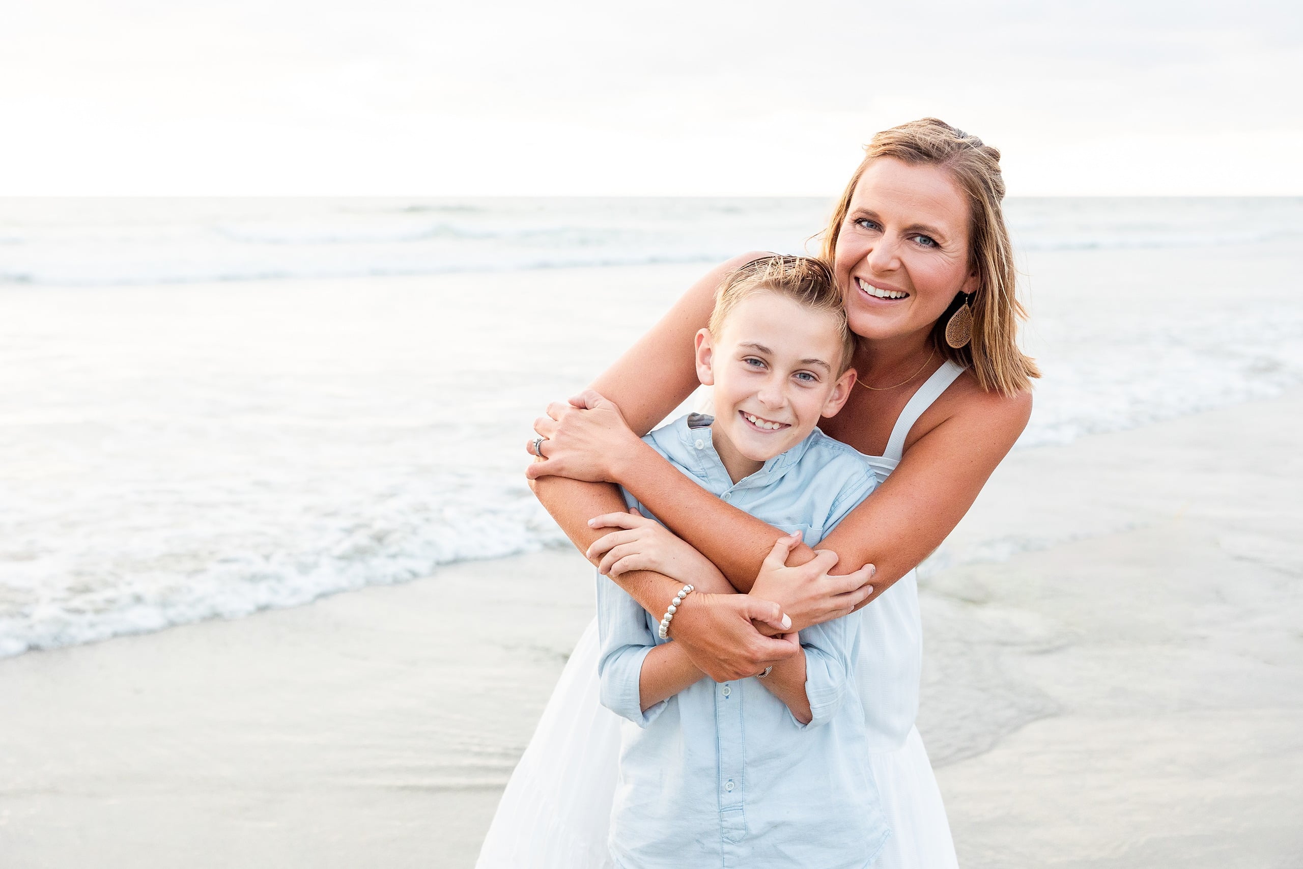 Butlers on the Beach — 15 Woman in white dress from behind, embracing boy at water's edge at beach