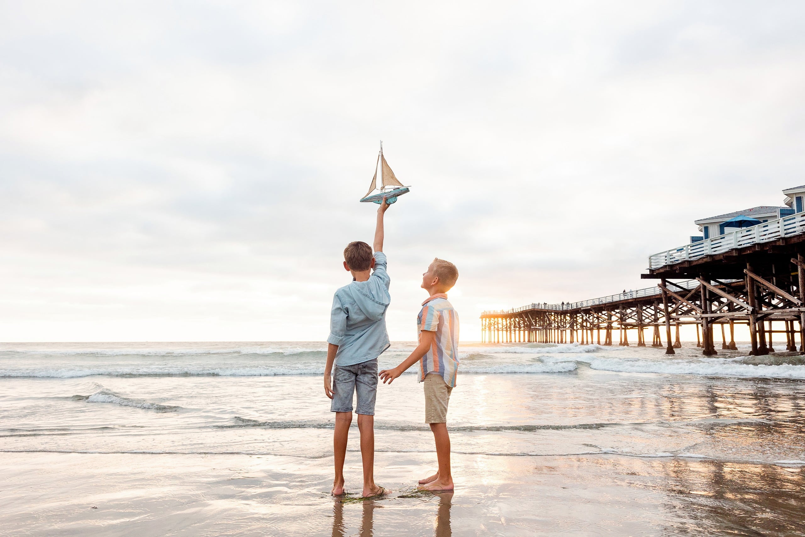 Butlers on the Beach — 20 Two boys standing at water's edge, one holding up sailboat toy at Crystal Pier