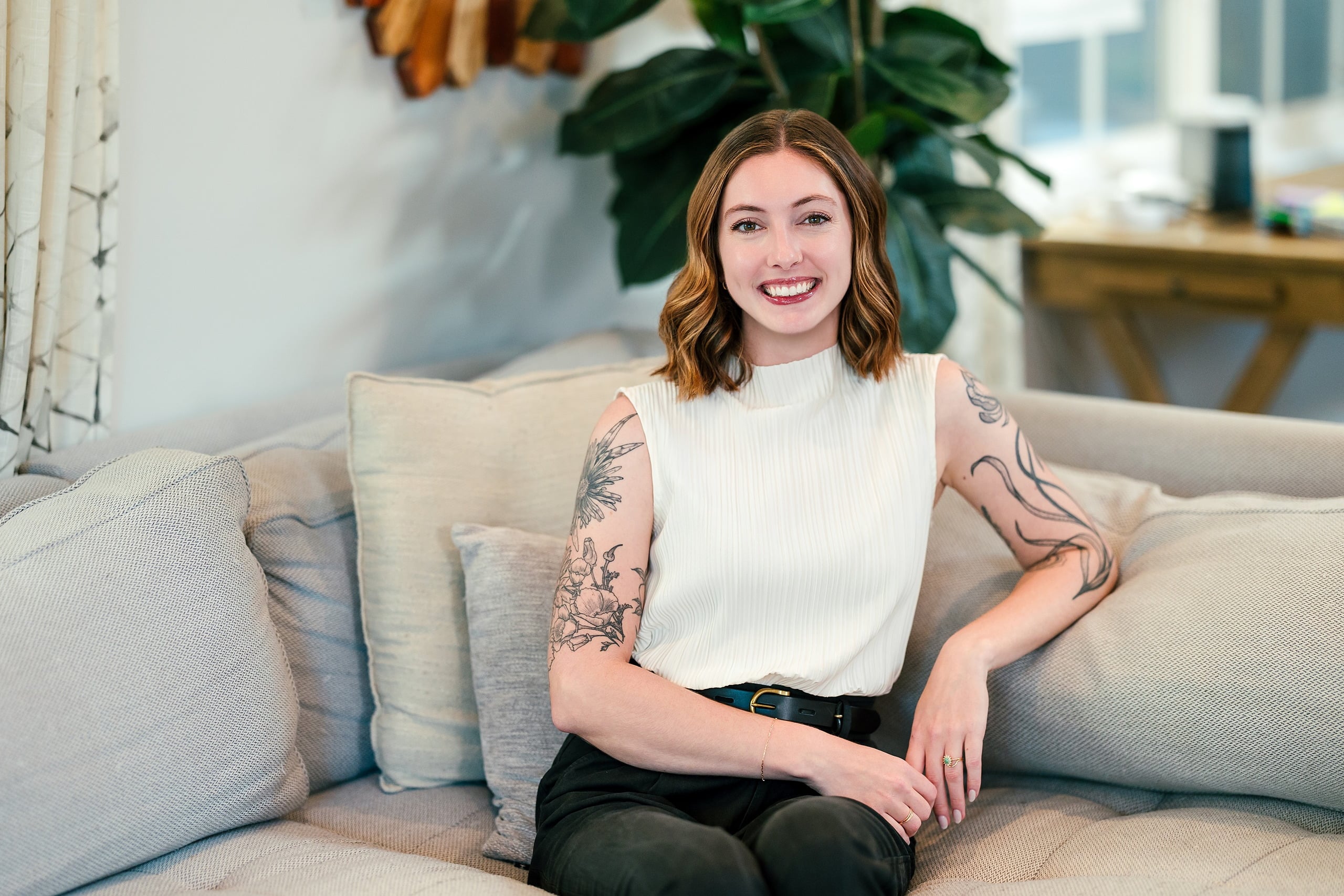 Capturing San Diego Spirit: Intention 2 Impact’s Team Retreat at Windansea — 03 Tattooed woman in cream sleeveless top relaxing on La Jolla Airbnb couch