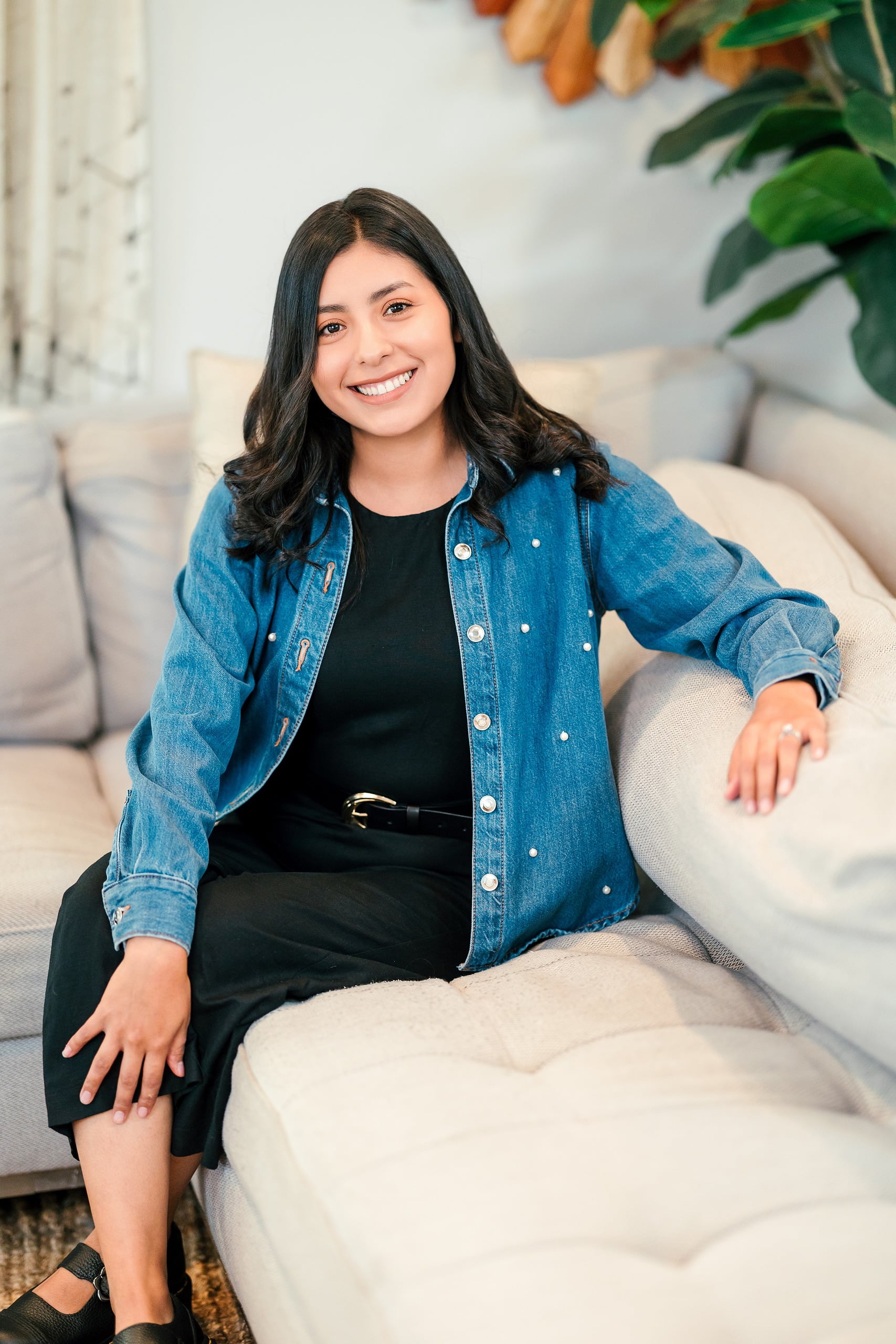 Capturing San Diego Spirit: Intention 2 Impact’s Team Retreat at Windansea — 05 Woman in denim jacket and black shirt perched on couch, grinning