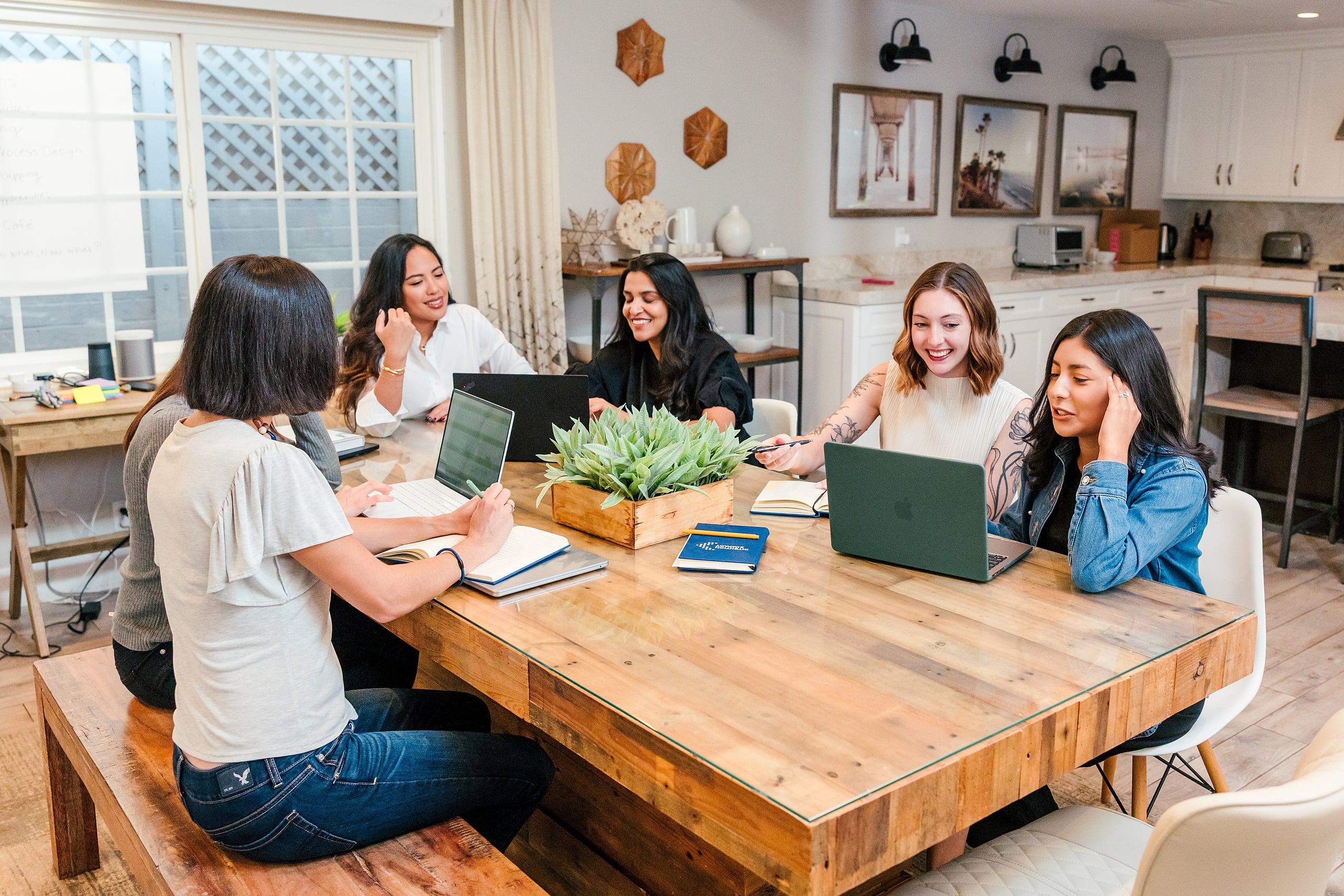 Capturing San Diego Spirit: Intention 2 Impact’s Team Retreat at Windansea — 07 Five women co-working at wooden table with laptops and notebooks